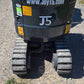 Rear undercarriage view of JoyT5 mini excavator showing durable rubber tracks, protected hydraulic lines and J5 branding, designed for compact construction, landscaping and utility projects across Canada
