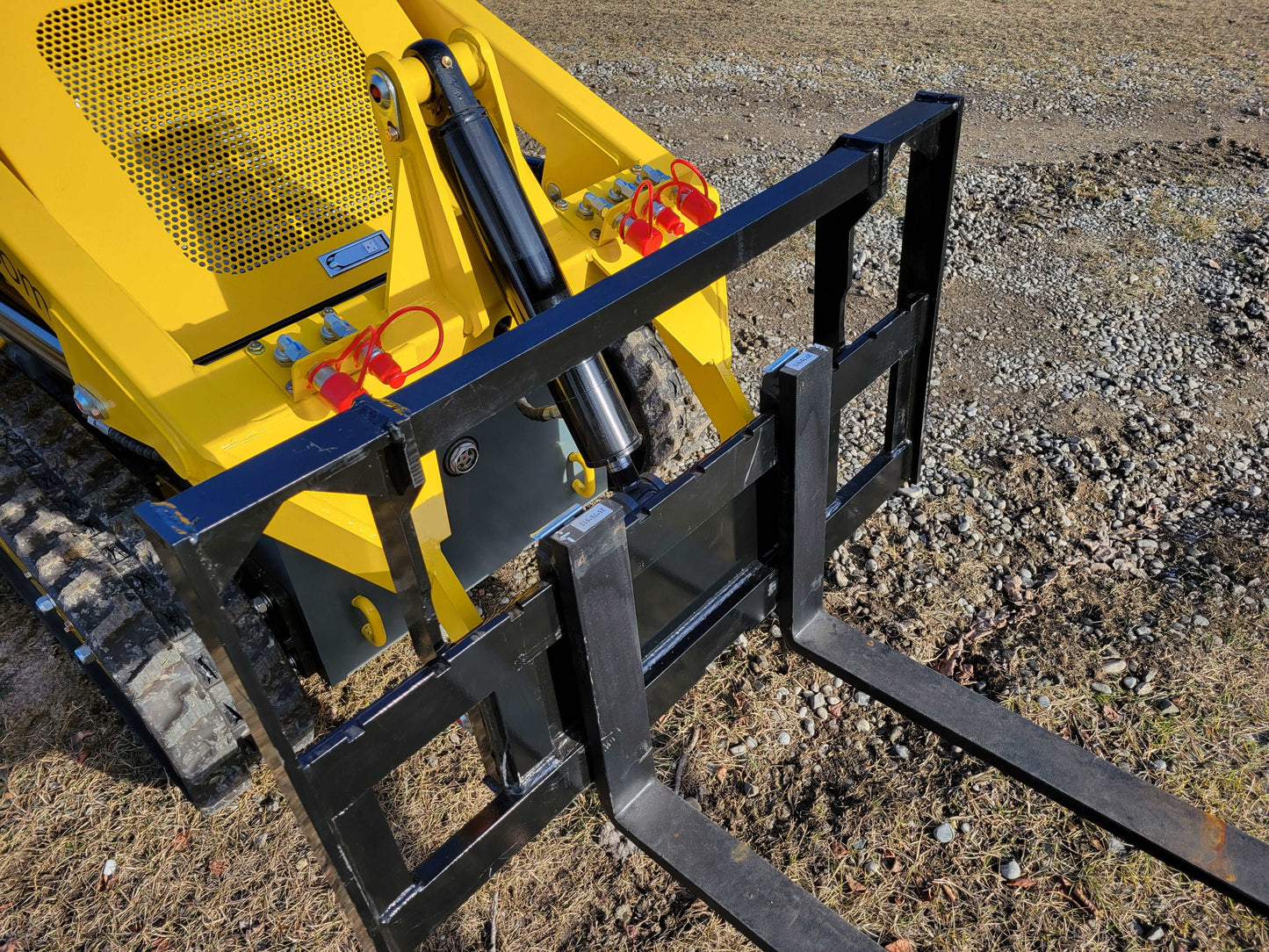 Close-up of JoyT5 mini skid steer loader showing hydraulic pallet fork attachment