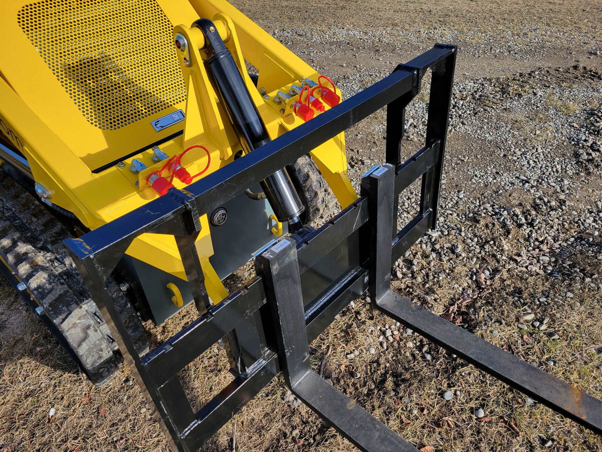 Close-up of JoyT5 mini skid steer loader showing hydraulic pallet fork attachment