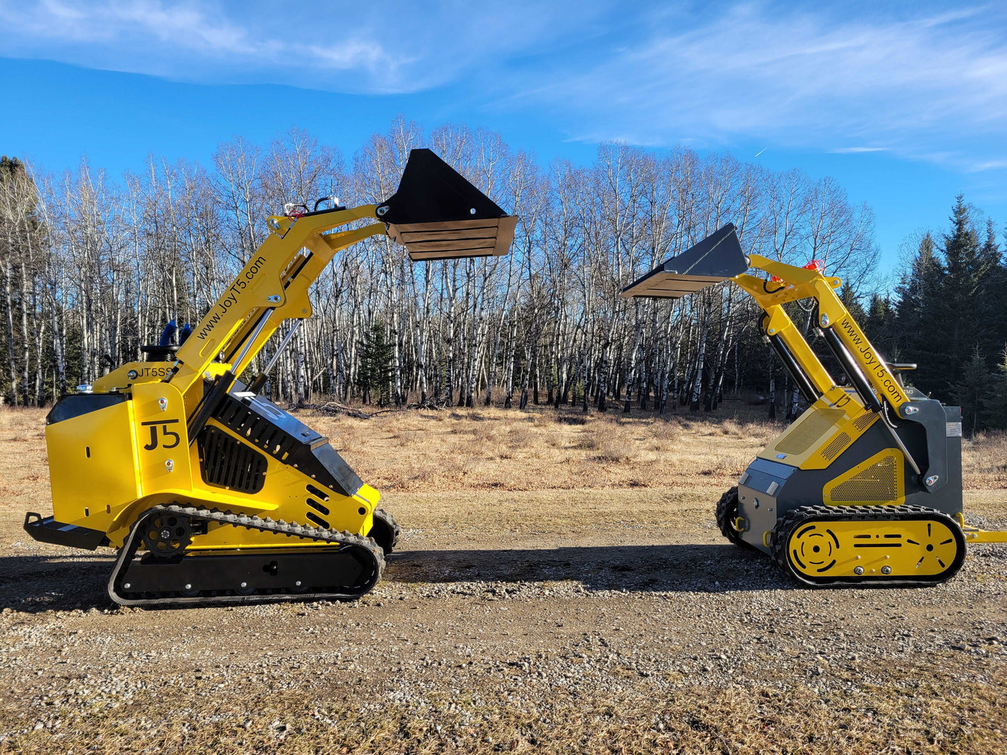 Side view of JoyT5 mini skid steer loaders with tracks and wheels lifting buckets outdoors.