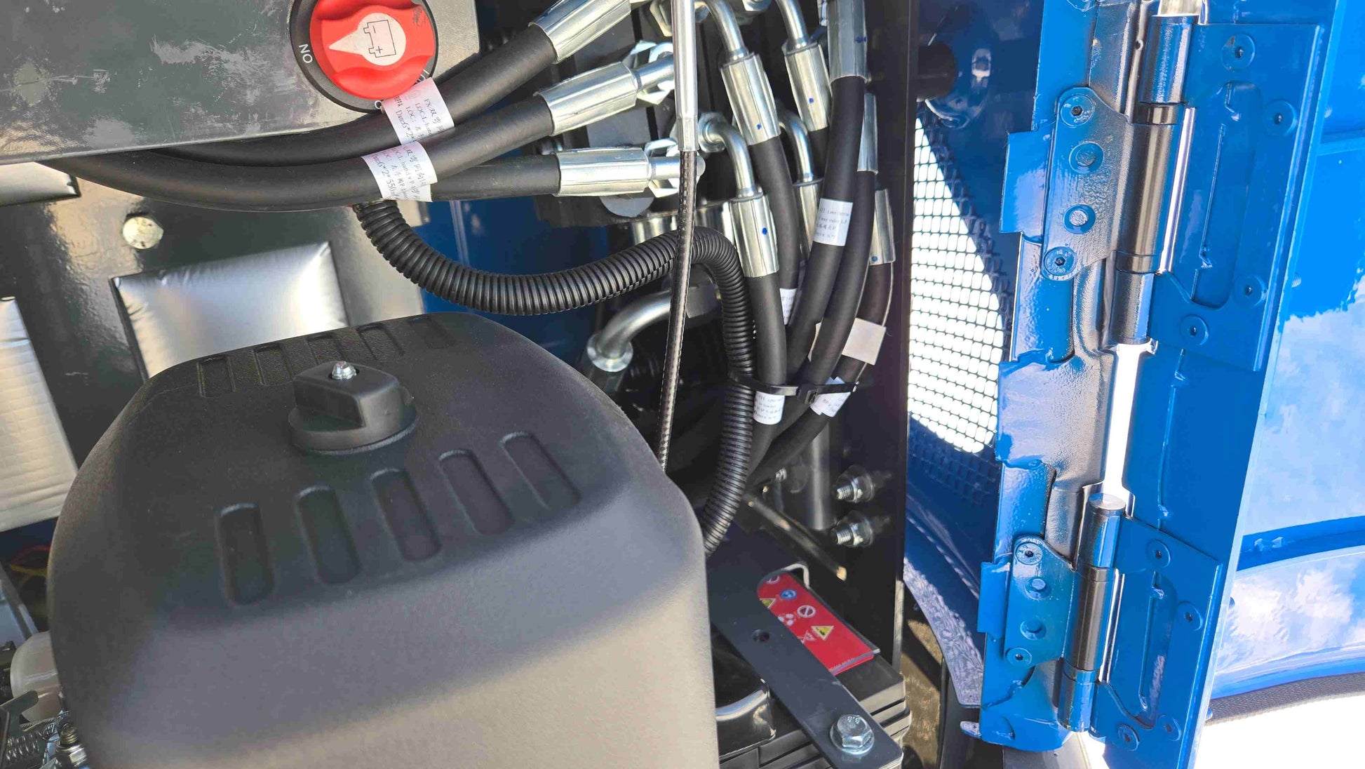 JoyT5 Rippa R10 mini excavator engine compartment showing hydraulic hoses wiring and components in cold snowy Canada