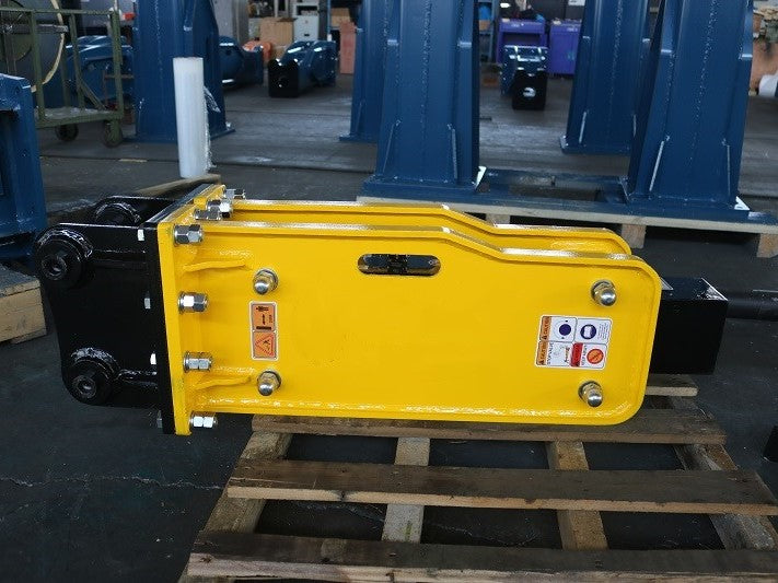 Yellow JoyT5 hydraulic breaker hammer excavator attachment placed on wooden pallet in warehouse