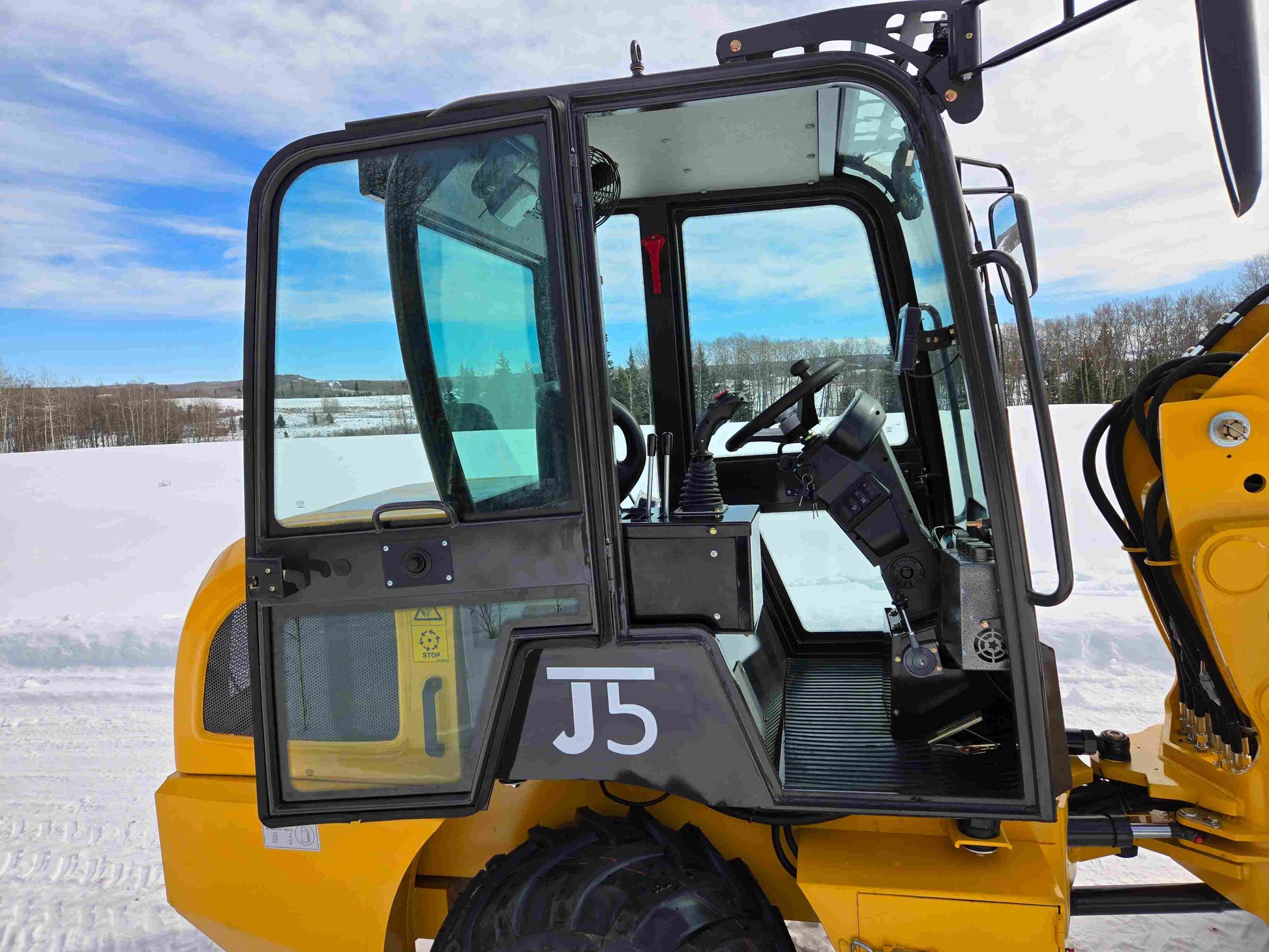 Side view of JT5 wheel loader cabin with open door showing operator seat and control panel.