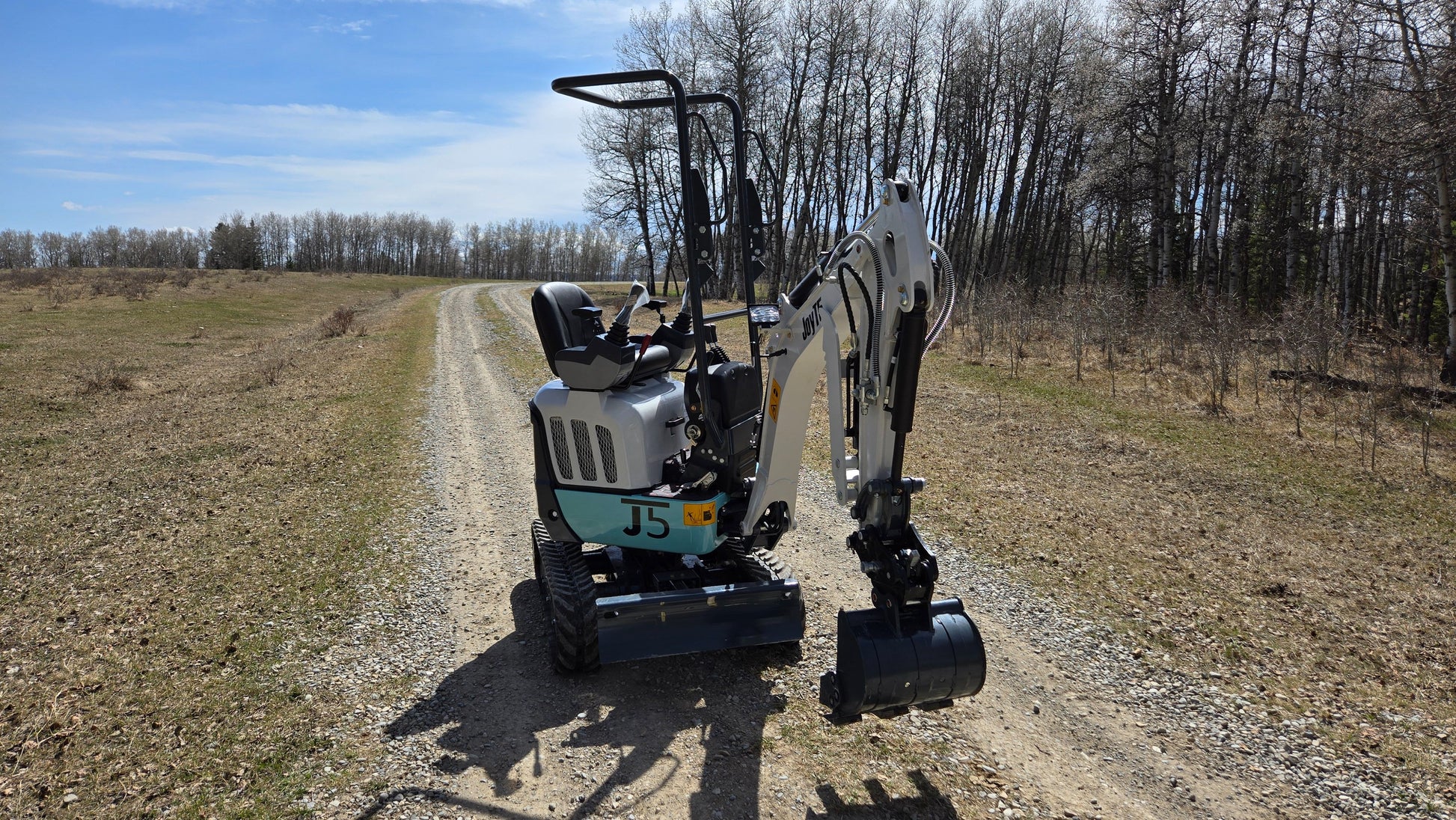 JT5120P 1.2 Ton mini excavator angled rear front view with open operator seat, zero tail swing, durable rubber tracks, and digging arm extended for compact construction and landscaping tasks.
