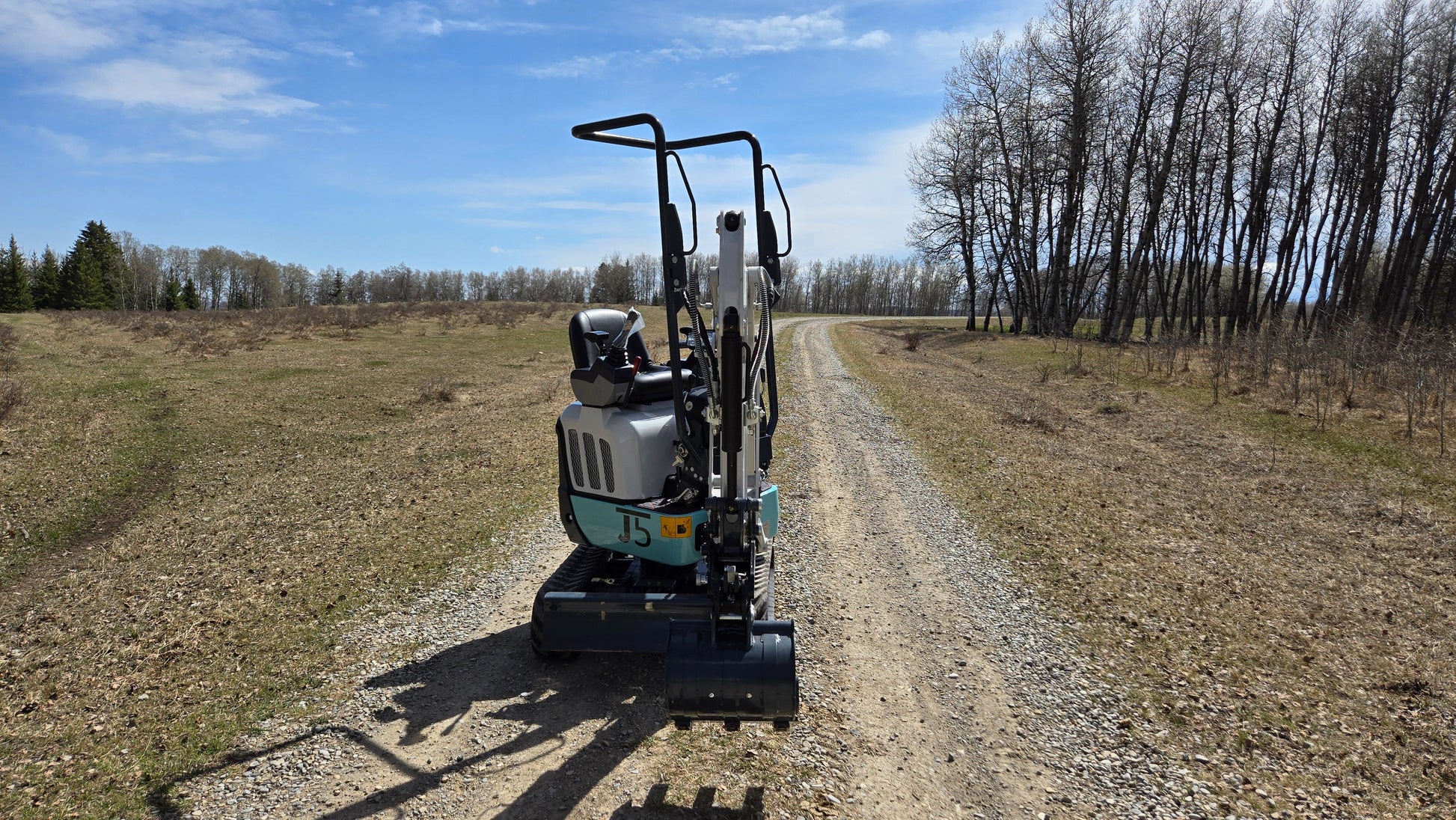 JT5120P 1.2 ton mini excavator back view driving on gravel road in Canada with JoyT5 compact zero tail digger support
