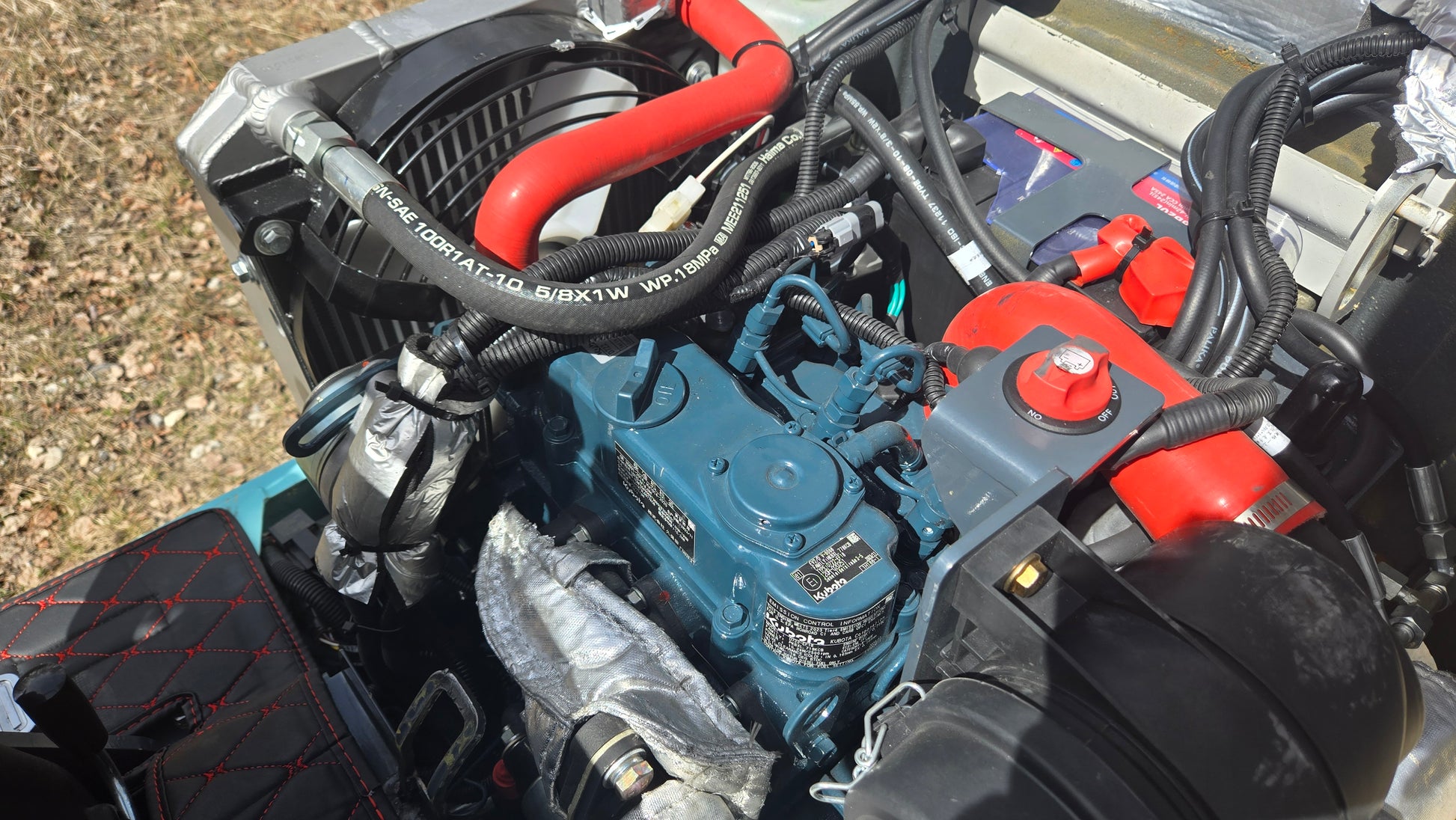 Detailed view of JT5120P mini excavator diesel engine with cooling fan, wiring, and fuel system components.
