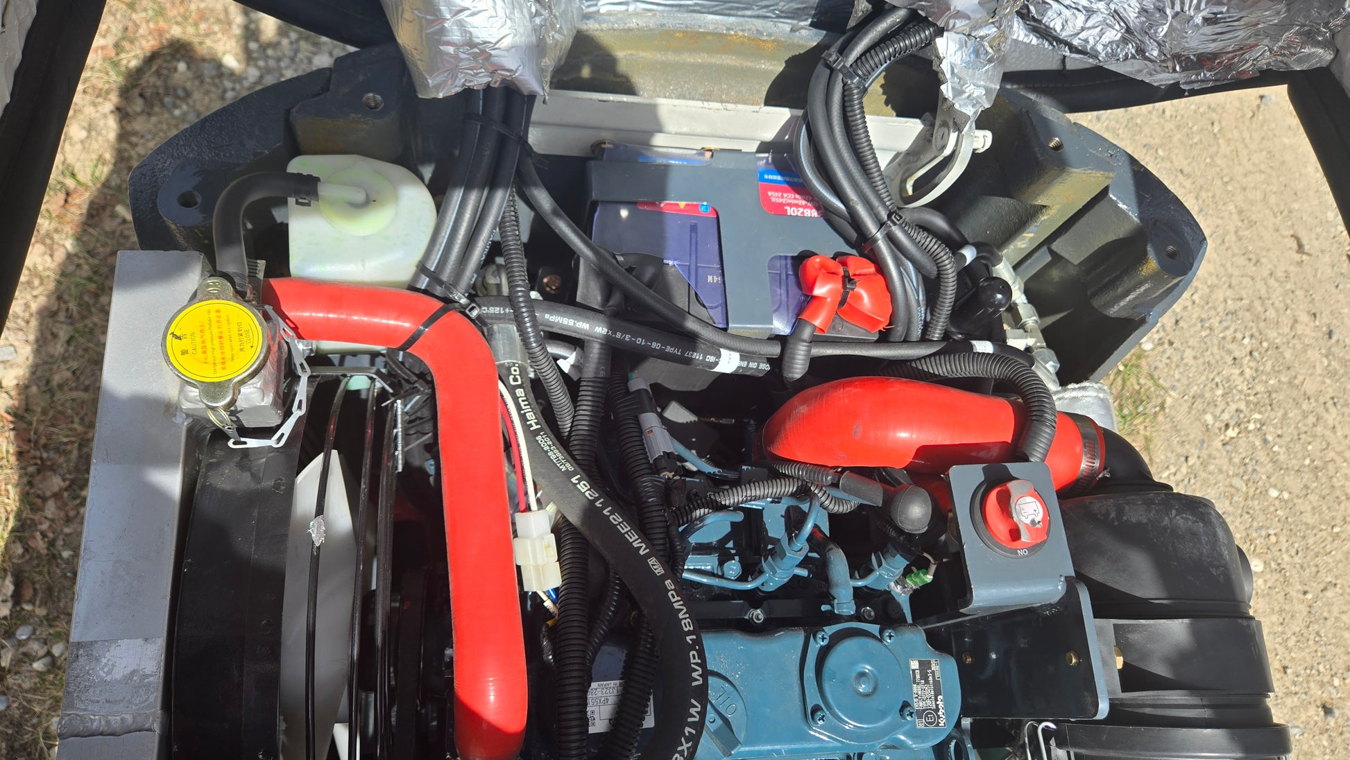 Top view of JT5120P mini excavator engine with radiator, battery, and red cooling hoses.
