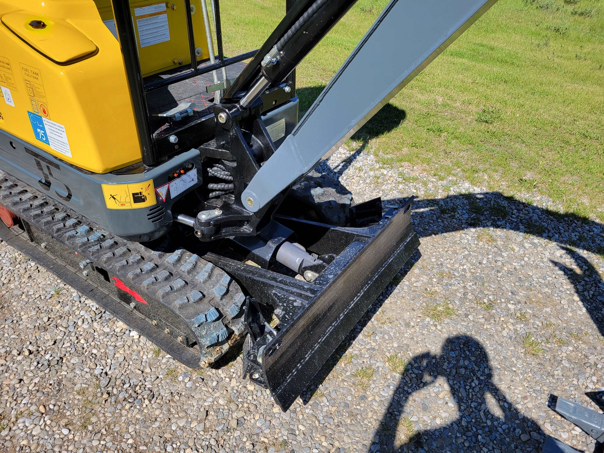 Close-up view of JoyT5 JT5200 2 ton mini excavator with Kubota D902 engine, showing hydraulic blade, rubber track, and boom joint for compact construction and landscaping work.

