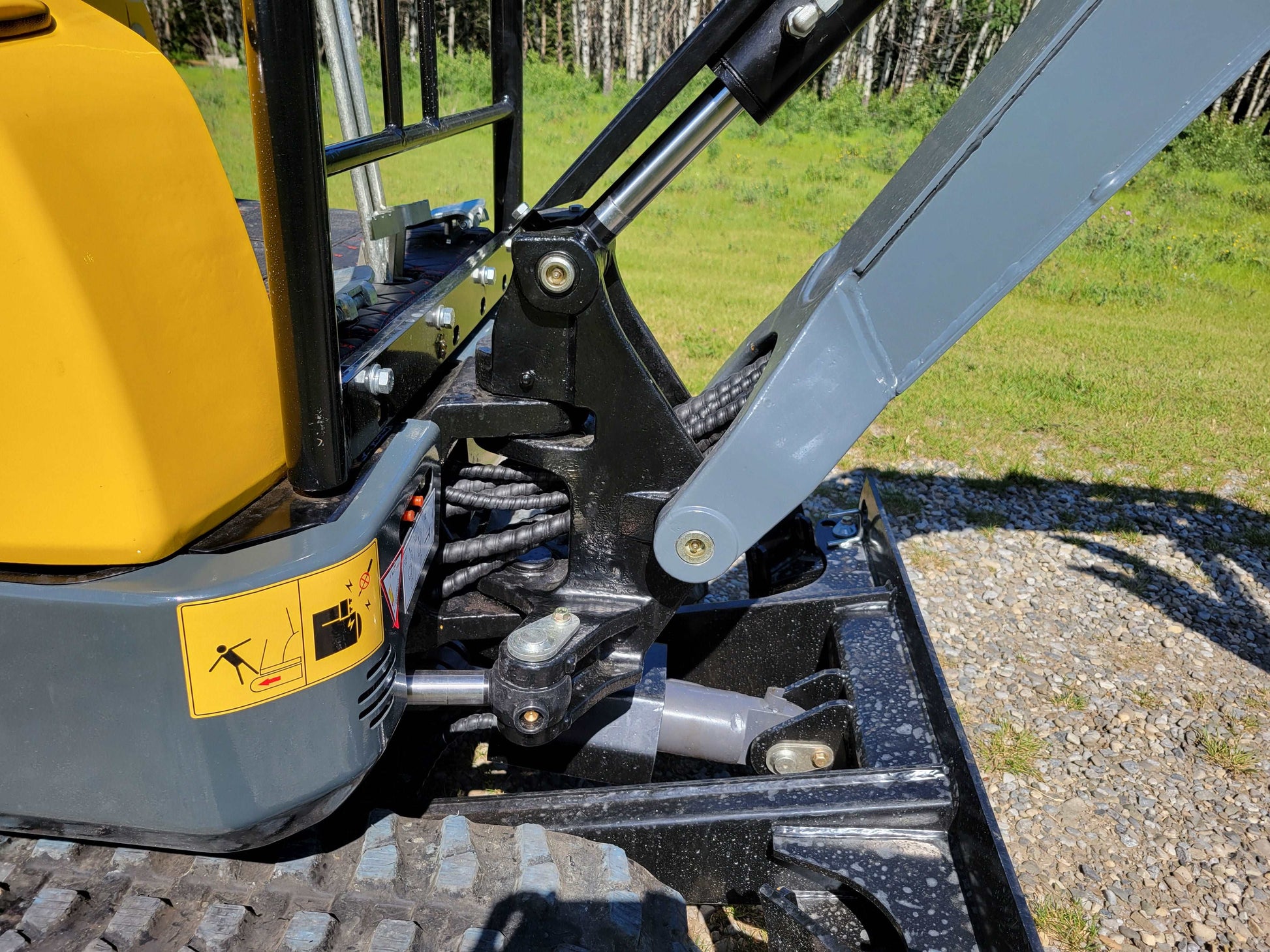 Close-up of JoyT5 JT5200 2 ton mini excavator boom and hydraulic cylinder powered by Kubota D902 engine, showing durable side swing boom and zero-tail design.
