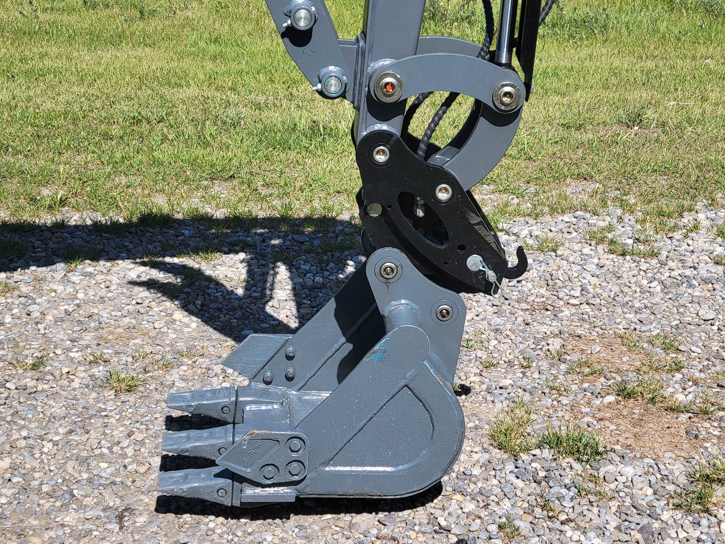 JoyT5 JT5200 2 ton mini excavator bucket with quick hitch and hydraulic thumb, showing strong digging teeth for landscaping and construction work.
