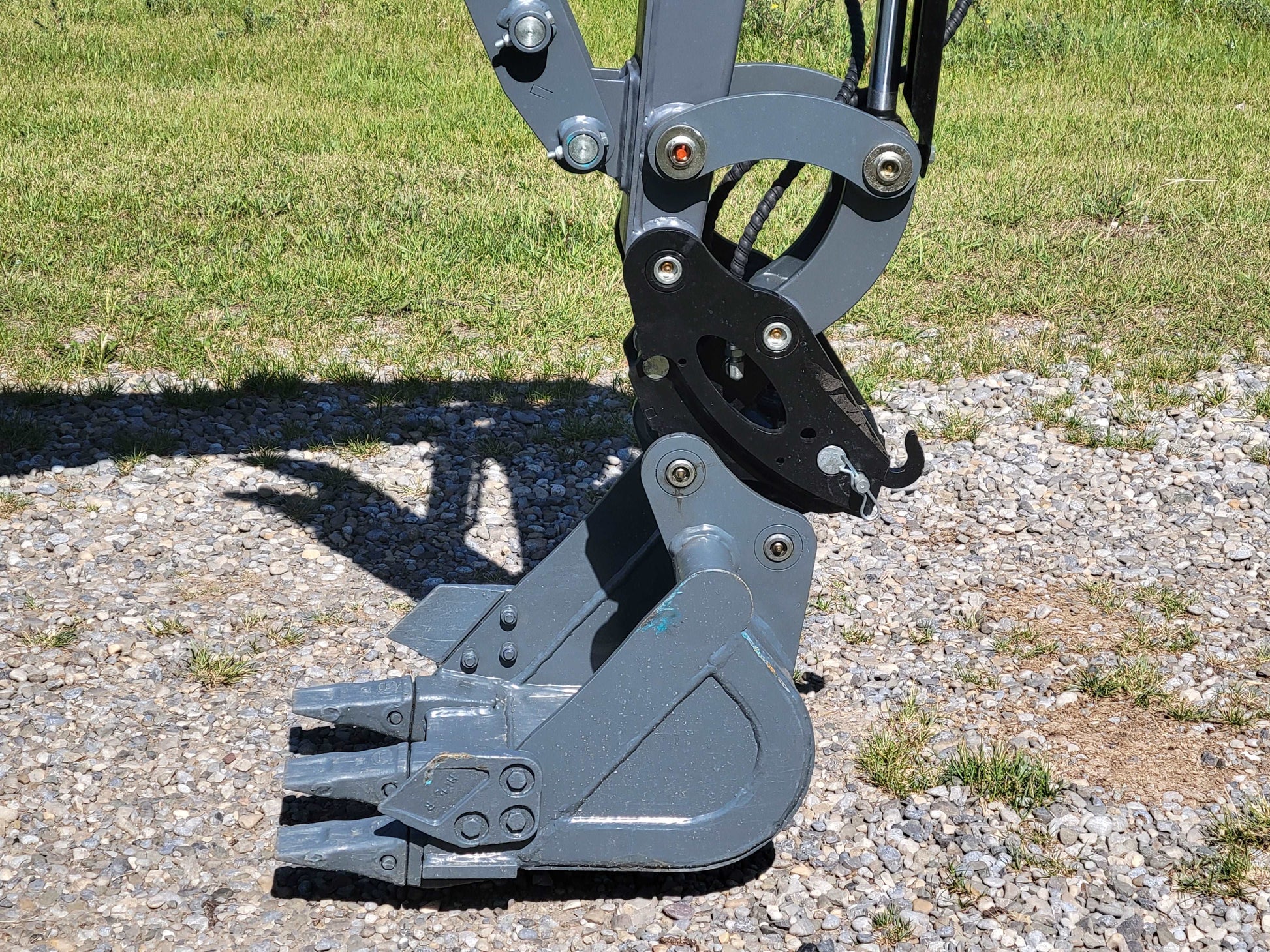 JoyT5 JT5200 2 ton mini excavator bucket with quick hitch and hydraulic thumb, showing strong digging teeth for landscaping and construction work.
