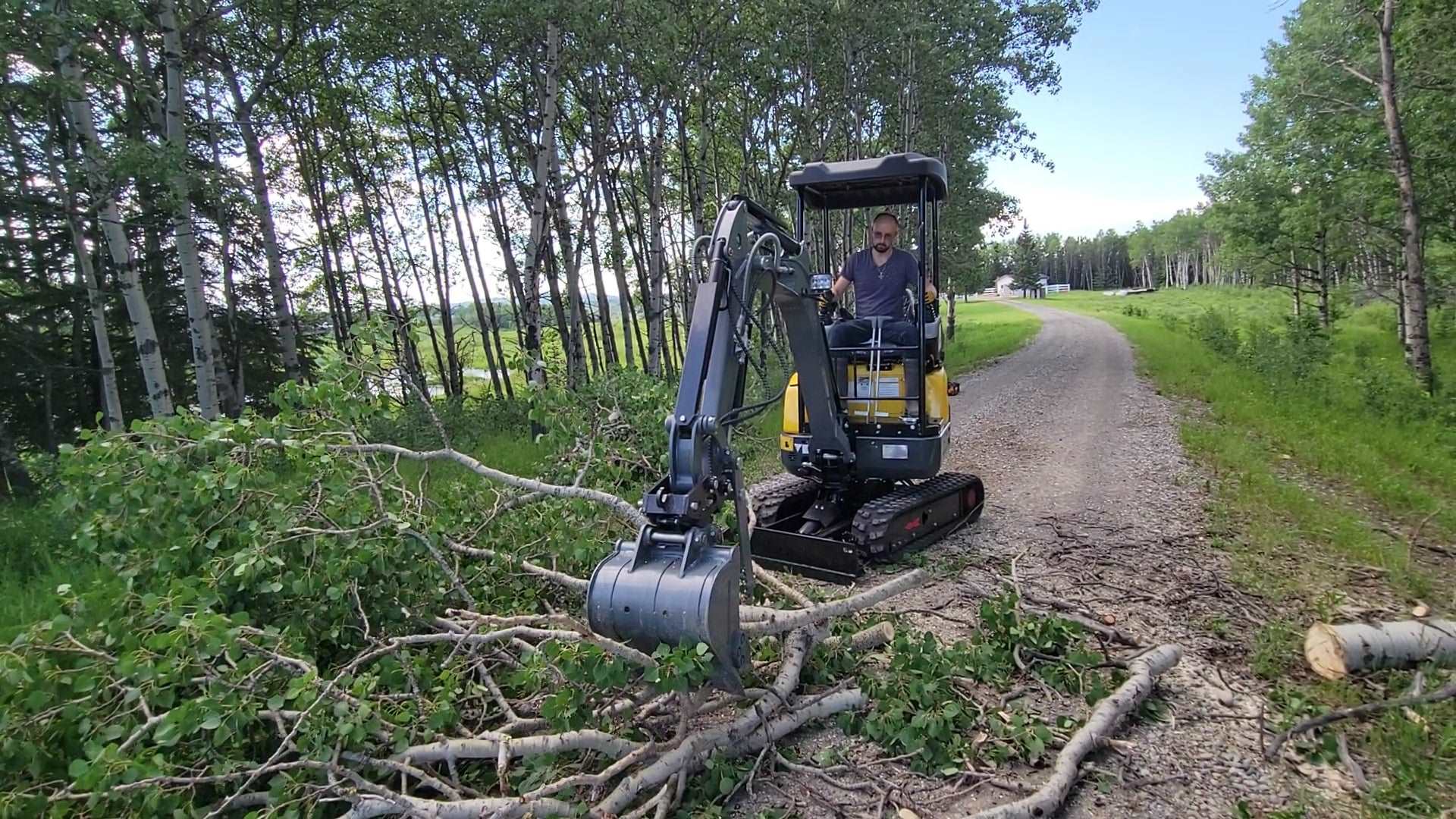 JT5200 2 ton mini excavator for sale with Kubota D902 engine, JoyT5 compact digger clearing fallen trees. Zero-tail small excavator with side swing boom and hydraulic thumb, available in Canada and USA.
