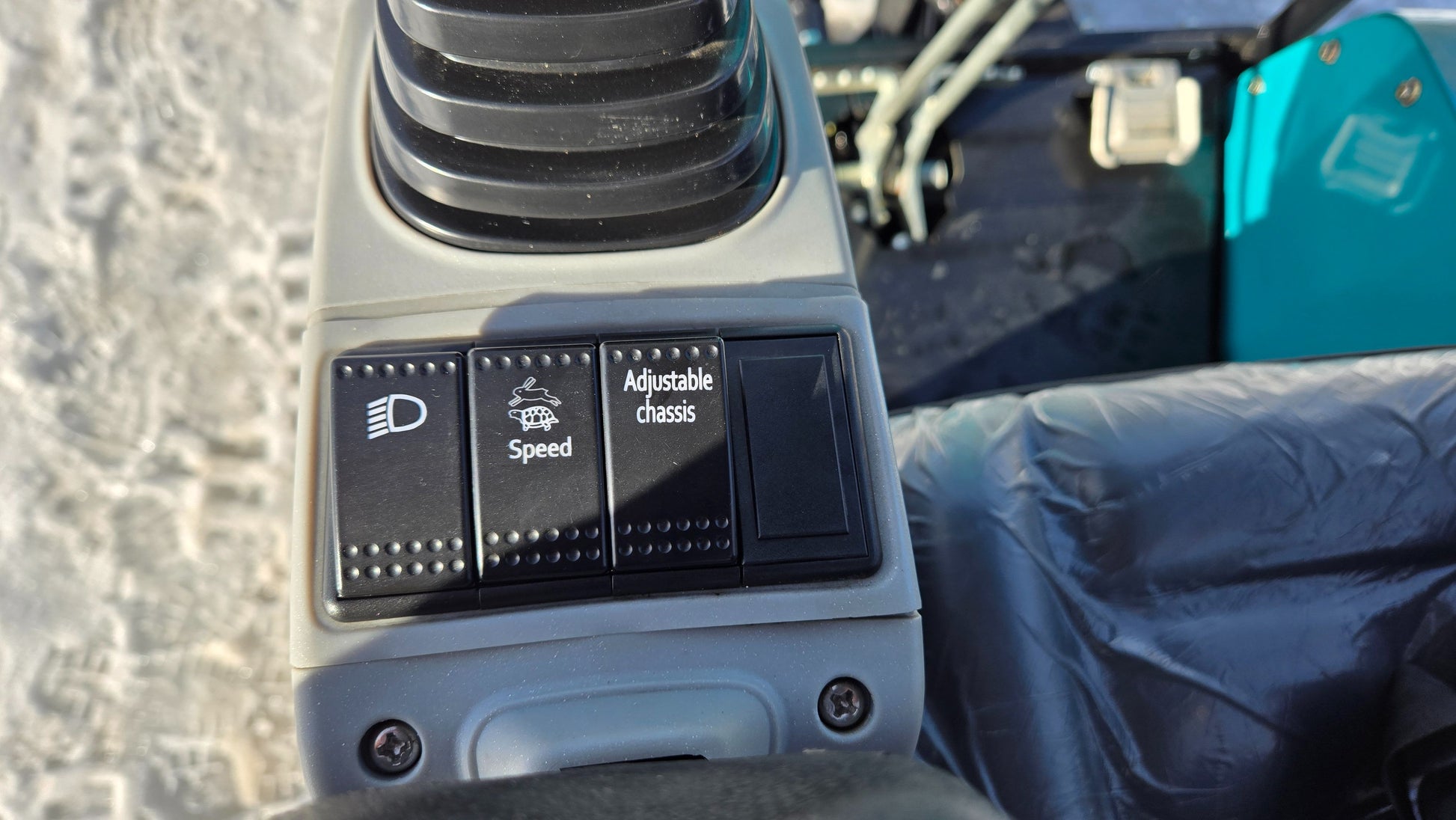 Close-up of control panel switches on JoyT5 JT5200 2 ton mini excavator, featuring headlight, speed mode, and adjustable chassis functions.
