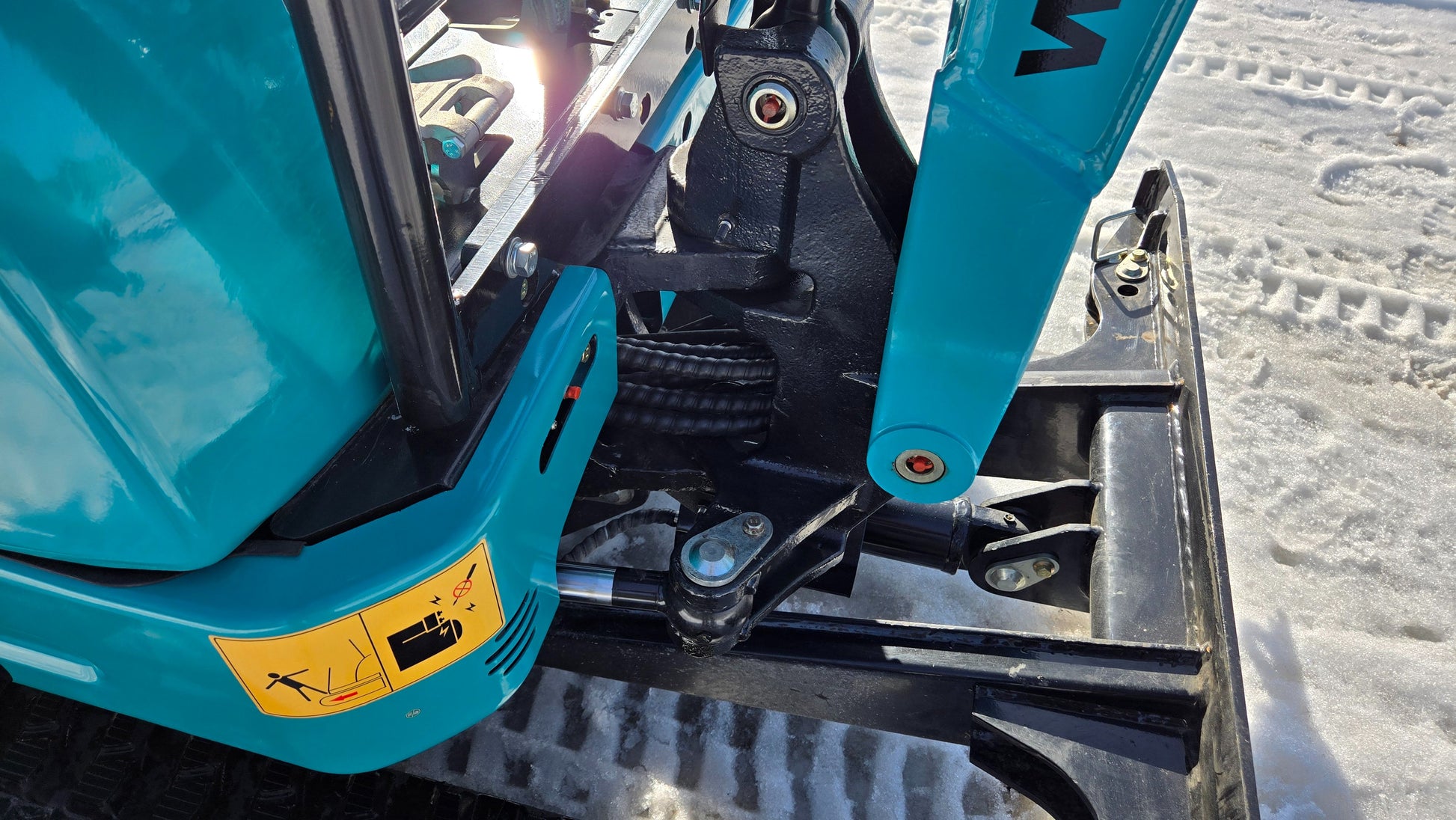 Close-up of JoyT5 JT5200 2 ton mini excavator hydraulic boom and side swing system. Kubota powered compact digger with zero-tail, U-boom and extendable undercarriage for construction and landscaping.
