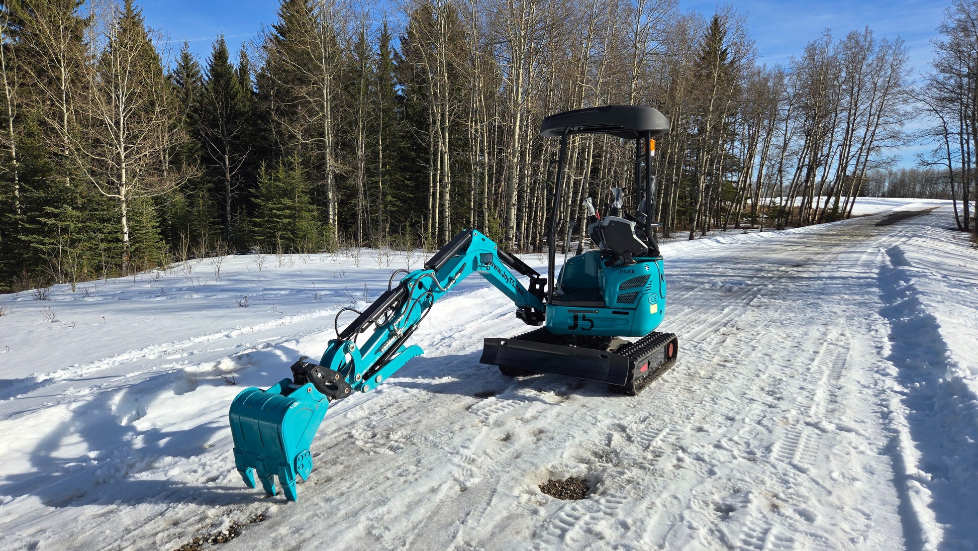 Rear view of JoyT5 JT5200 2 ton mini excavator with boom and bucket fully extended to the ground. Compact Kubota-powered digger designed for trenching, landscaping, and light construction projects.
