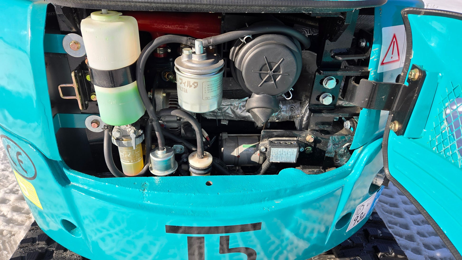 Engine compartment of JoyT5 JT5200 mini excavator with fuel filter, hydraulic components, and reservoir visible inside rear cover.
