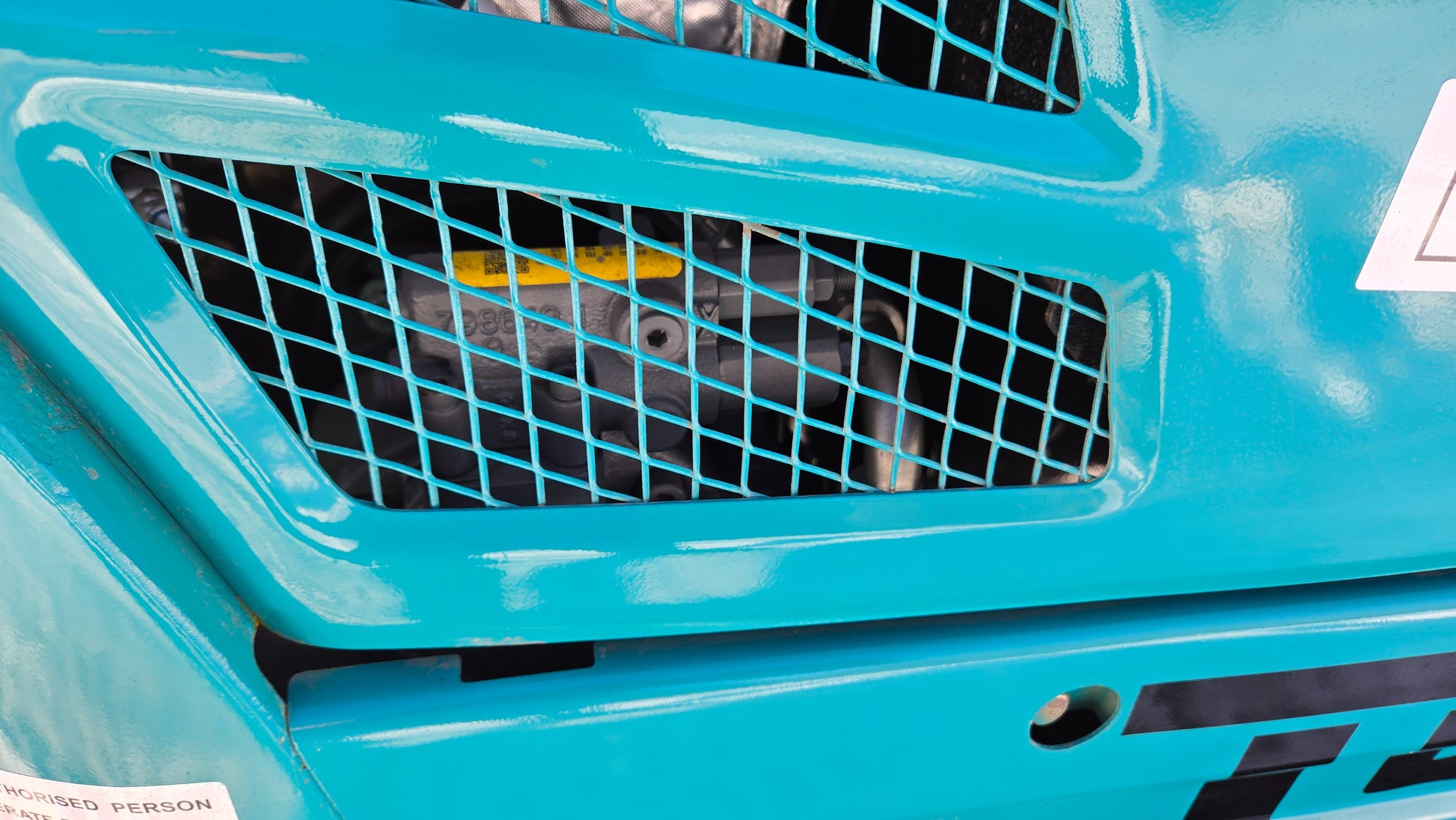 Side view of JoyT5 JT5200 mini excavator engine through protective metal ventilation grille.
