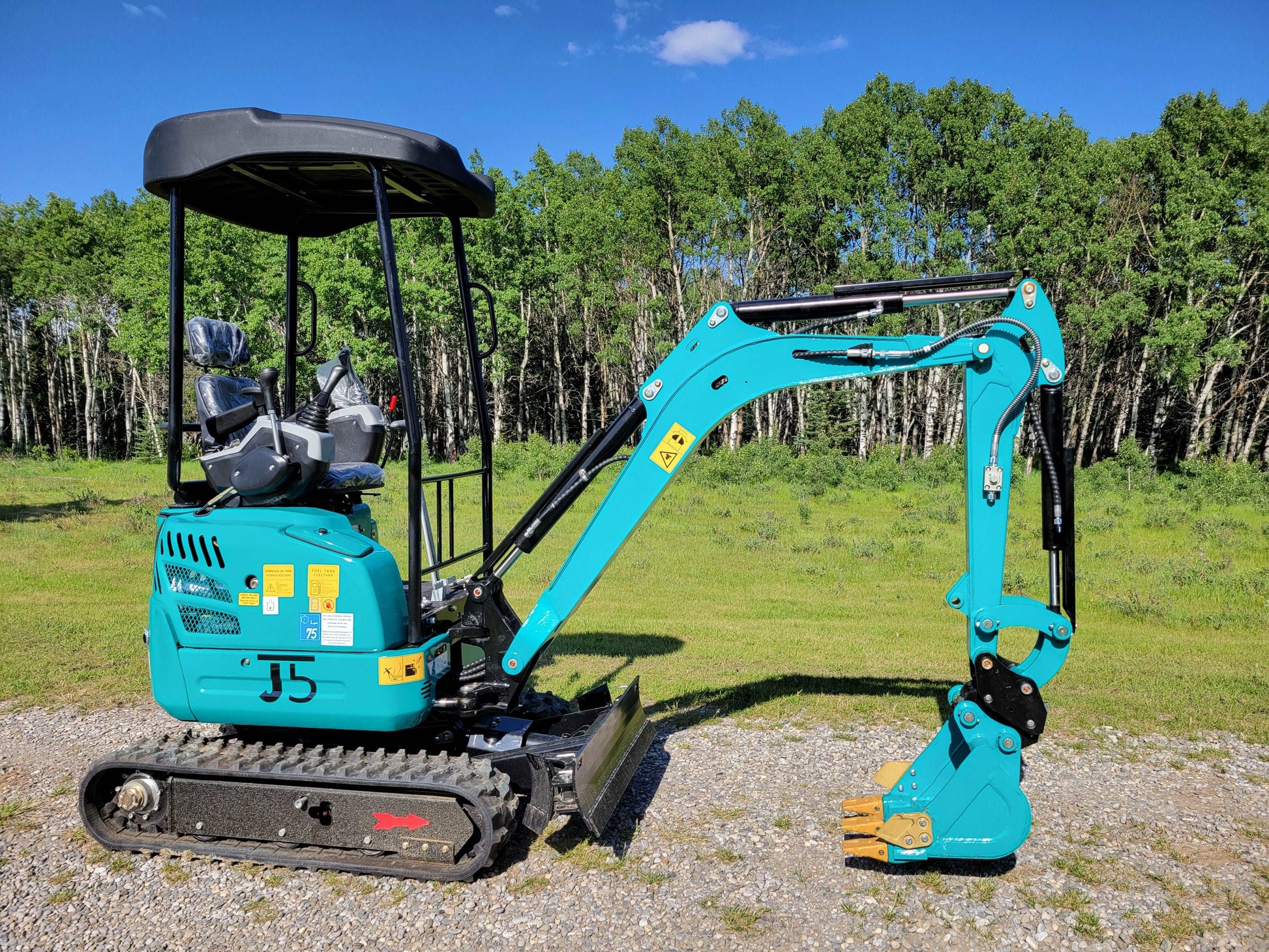 Close-up side view of JT5200 mini excavator in blue, highlighting digging arm, operator seat, and rubber track system for compact construction work.
