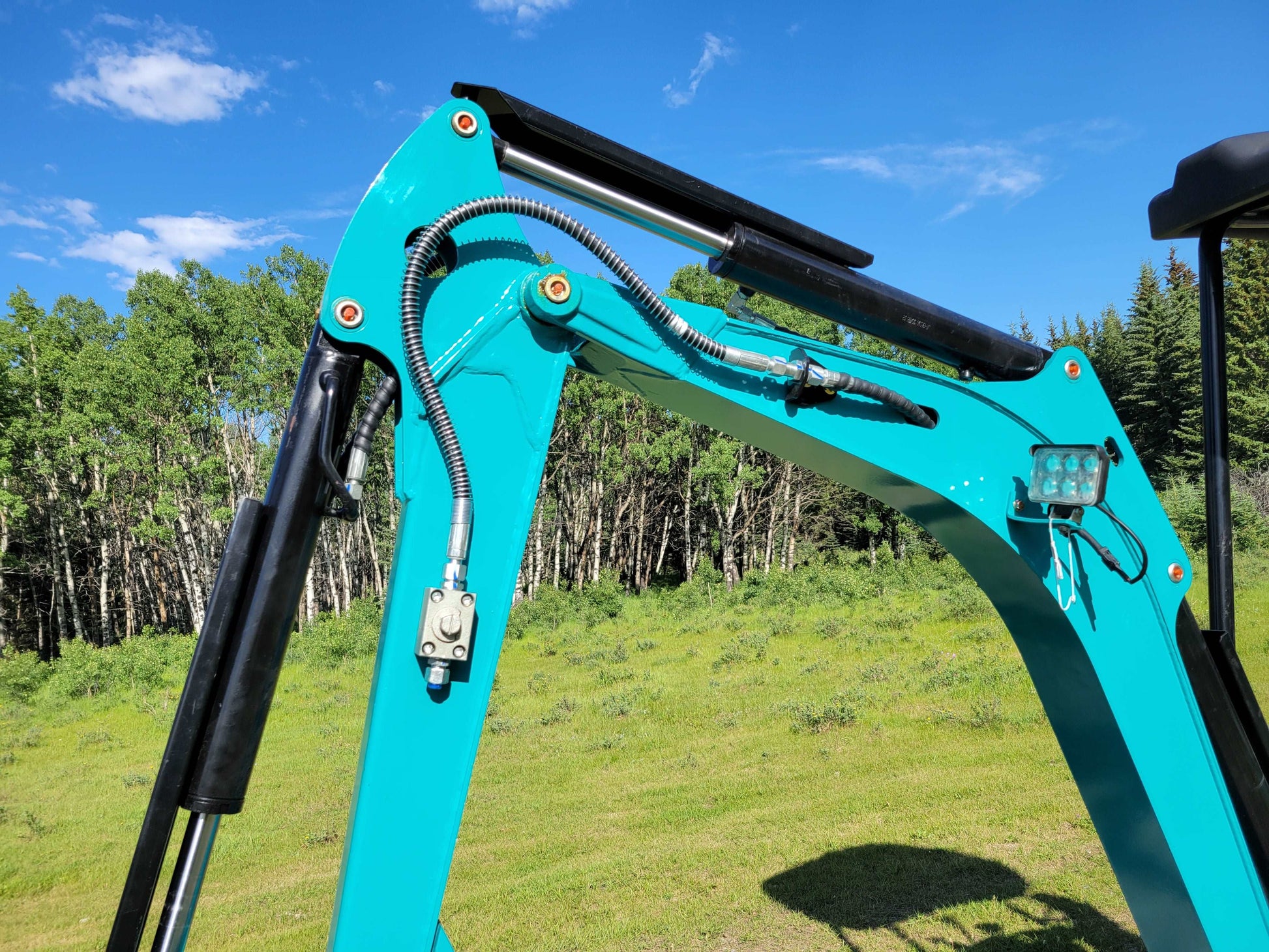 Close-up view of JT5200 mini excavator boom showing hydraulic cylinders, hoses, joints, and LED work light.
