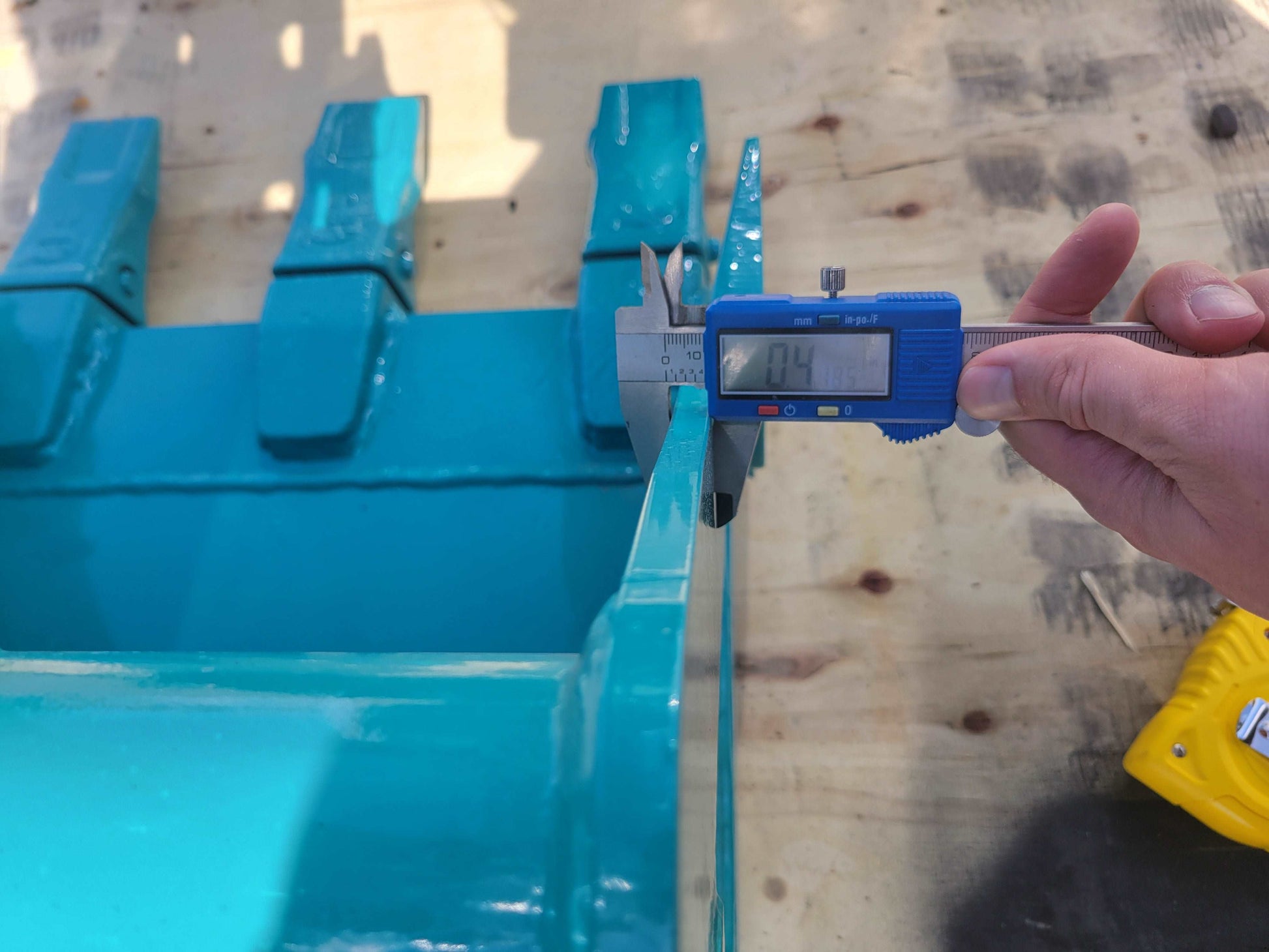 Digital caliper measuring the steel plate thickness of the JT5200 mini excavator bucket, showing 4mm for durability and strength.

