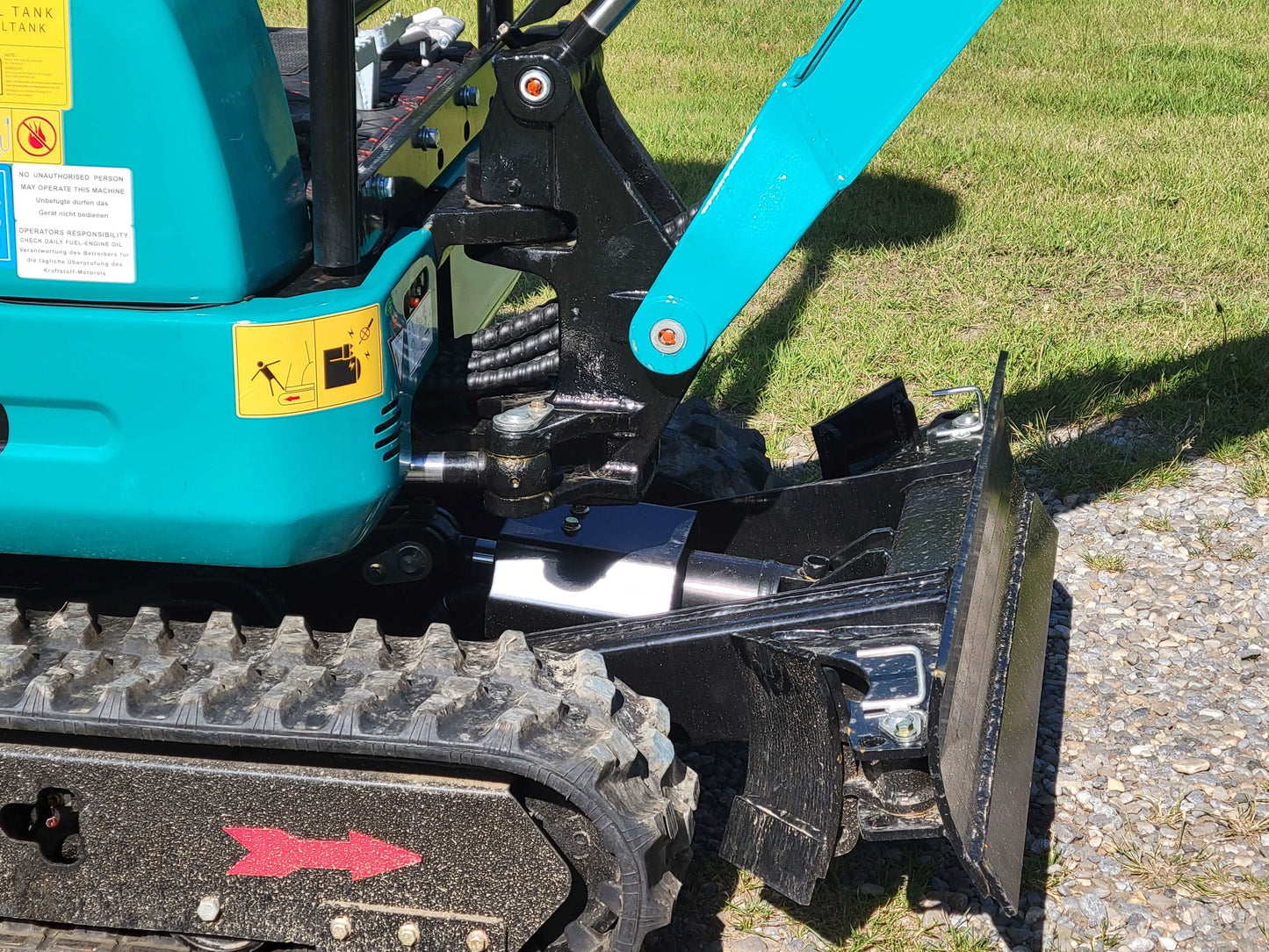 Close-up view of JT5200 mini excavator showing hydraulic joint, rubber track, and front dozer blade for compact digging and leveling.
