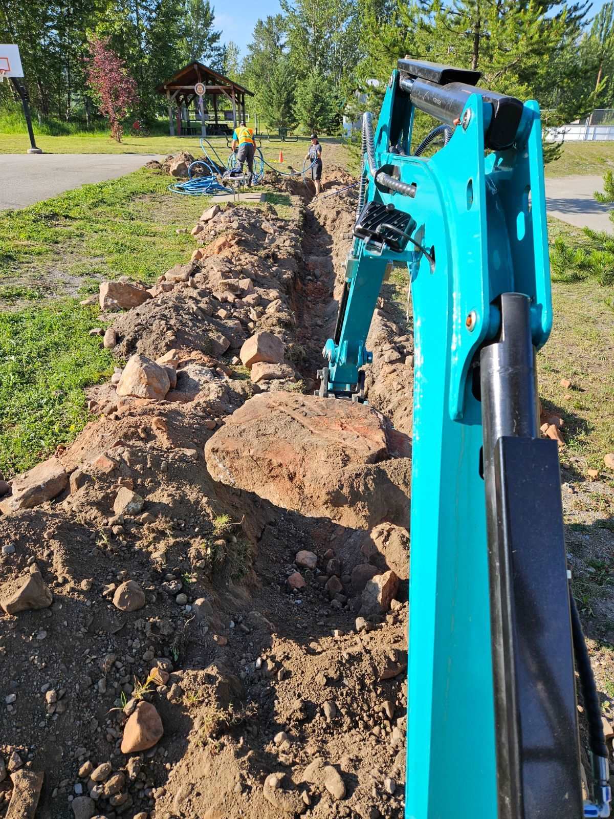 JoyT5 JT5200 2 ton mini excavator with Kubota D902 engine performing trench digging and removing rocks. Compact hydraulic digger with zero-tail swing, U-boom and side swing boom for construction, utility and landscaping work.
