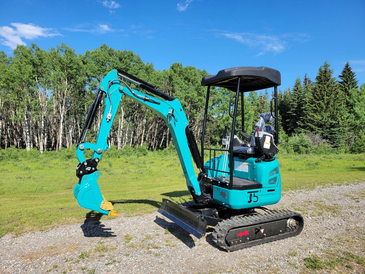 Left side view of JT5200 mini excavator with rubber tracks, operator canopy, front blade, and digging arm with bucket.
