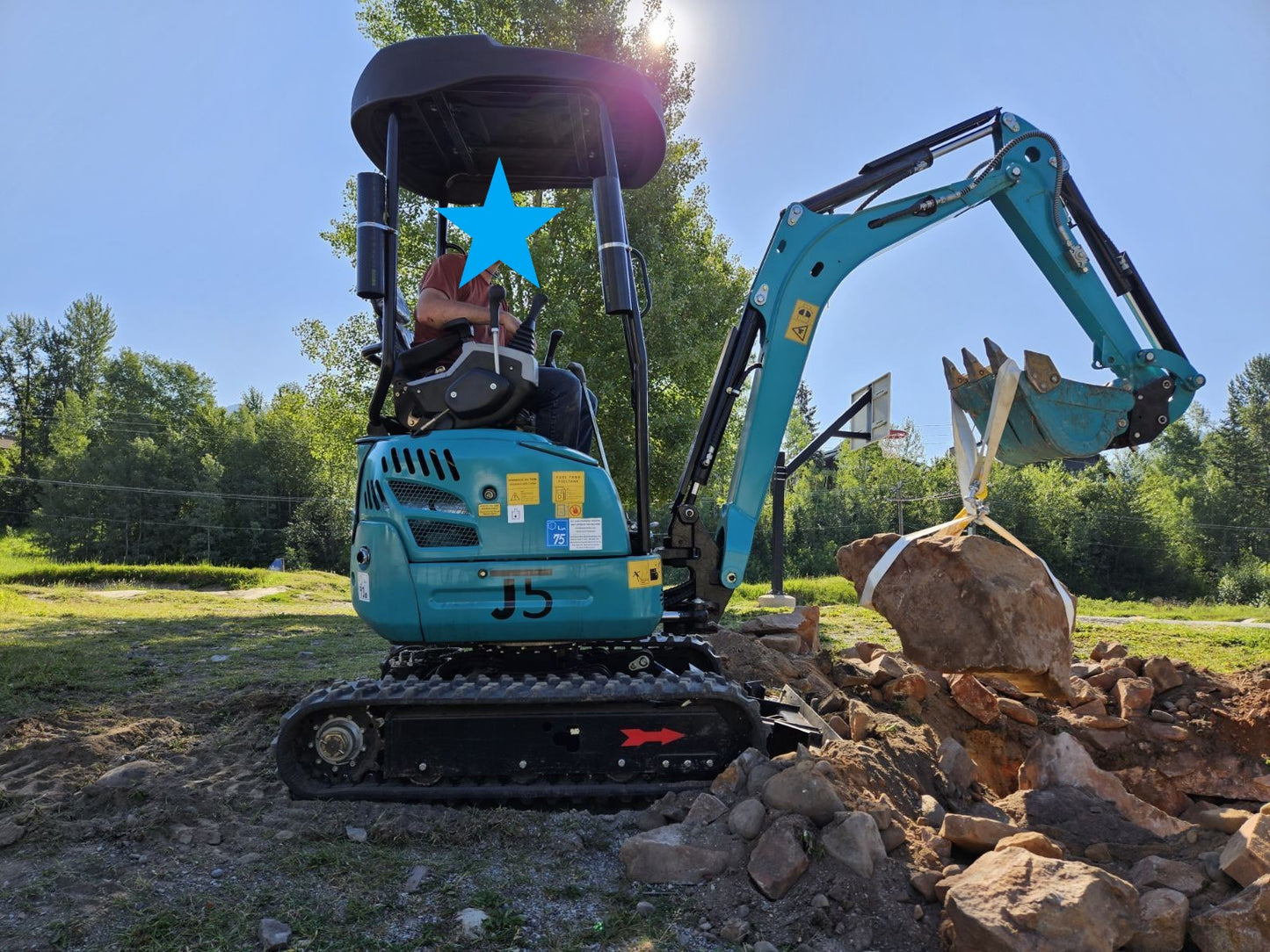JT5200 Special Edition 2 Ton Mini Excavator lifting a large boulder with hydraulic thumb. Compact Kubota engine digger with 4400 lbs capacity for construction, landscaping, and rocky ground projects.