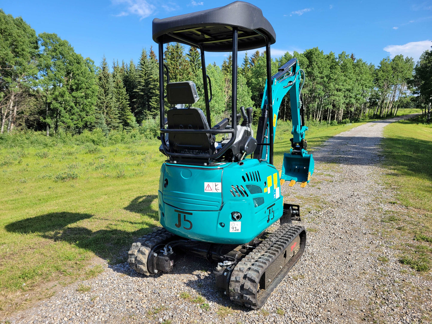 Rear side view of JT5200 mini excavator showing operator seat, protective canopy, rubber tracks, and digging bucket.
