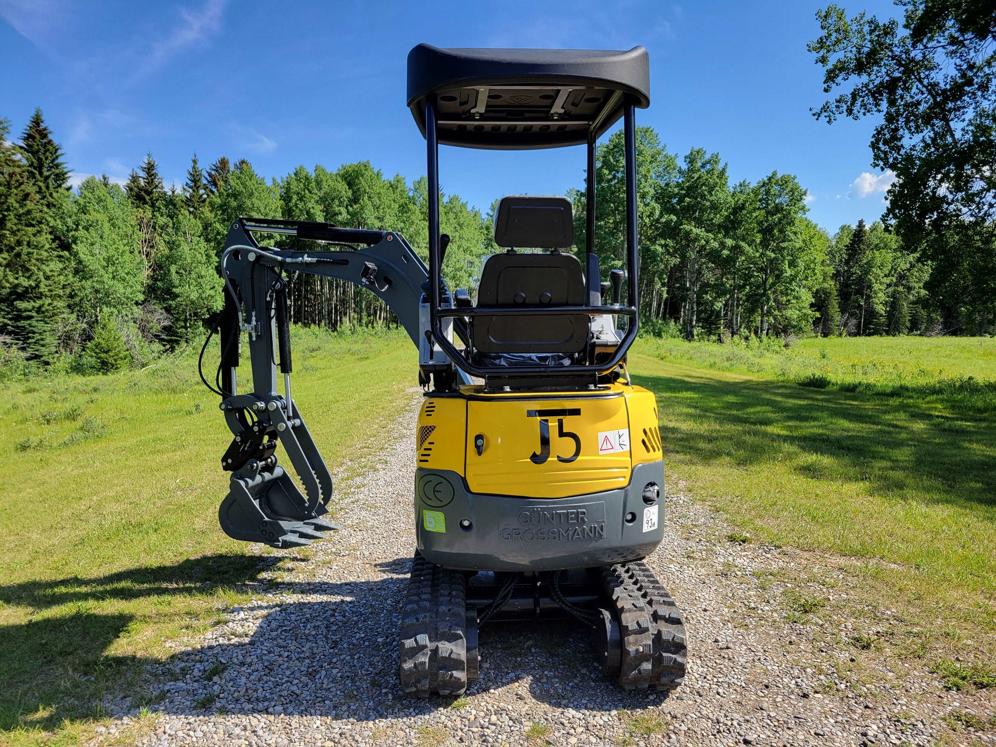 Rear view of JoyT5 JT5200 mini excavator with boom and bucket extended to the left side.
