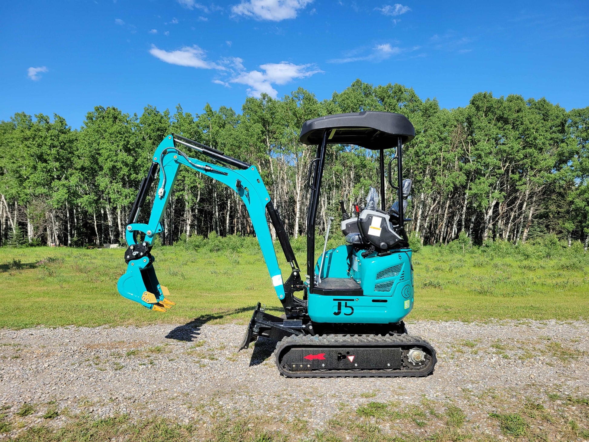 Right side view of JT5200 mini excavator showing rubber tracks, operator seat with canopy, and extended digging arm with bucket.
