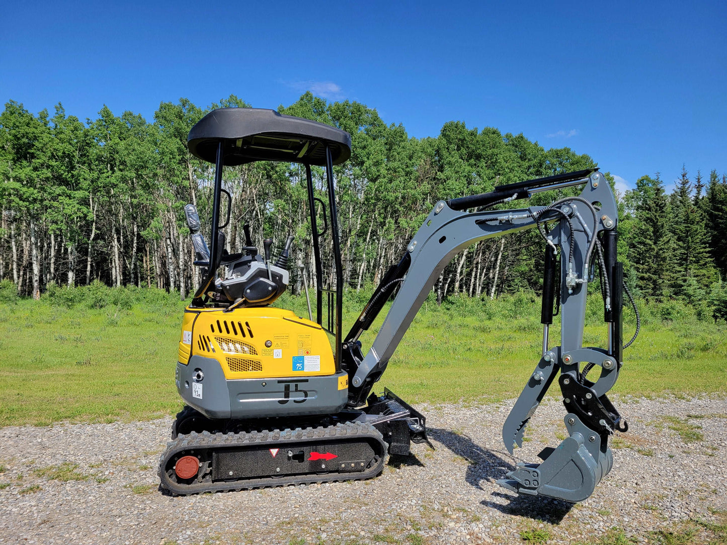 JoyT5 JT5200 mini excavator side view showing rubber tracks, engine housing, operator canopy, and digging arm with bucket.
