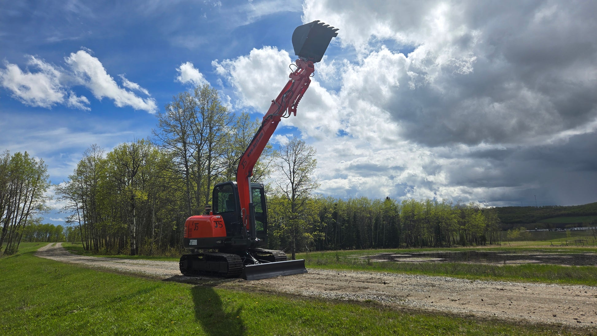 Side view of JT5600 JoyT5 6 Ton excavator with Yanmar engine lifting bucket high on construction site road