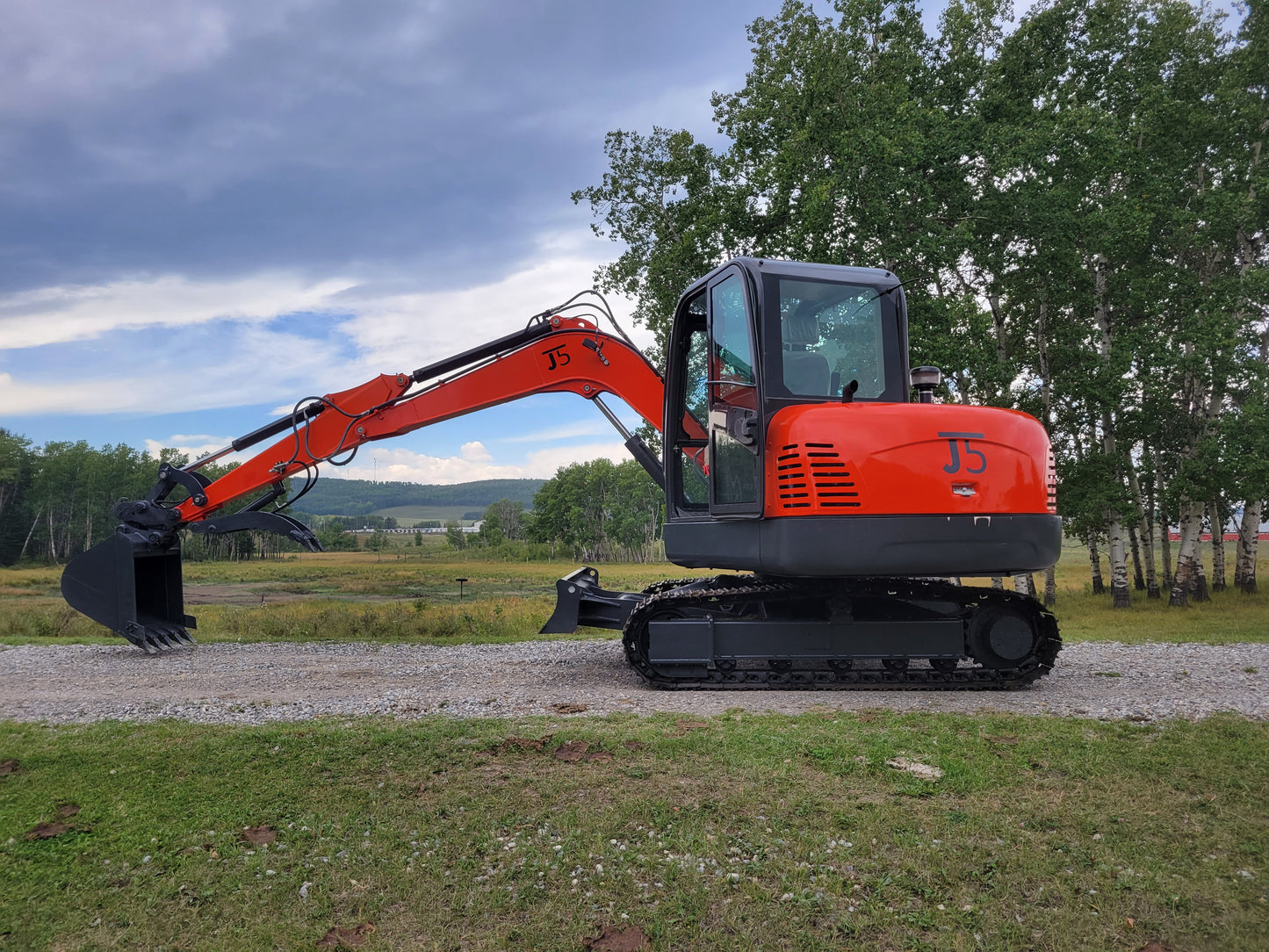 JT5600 mini excavator side profile showing full boom, bucket, and operator cabin with natural background
