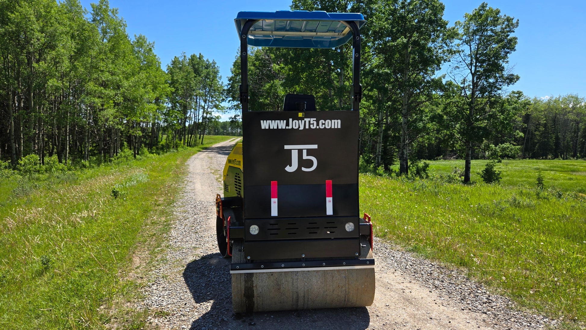 Rear view of JT5DR35 double drum road roller on gravel road with green forest background