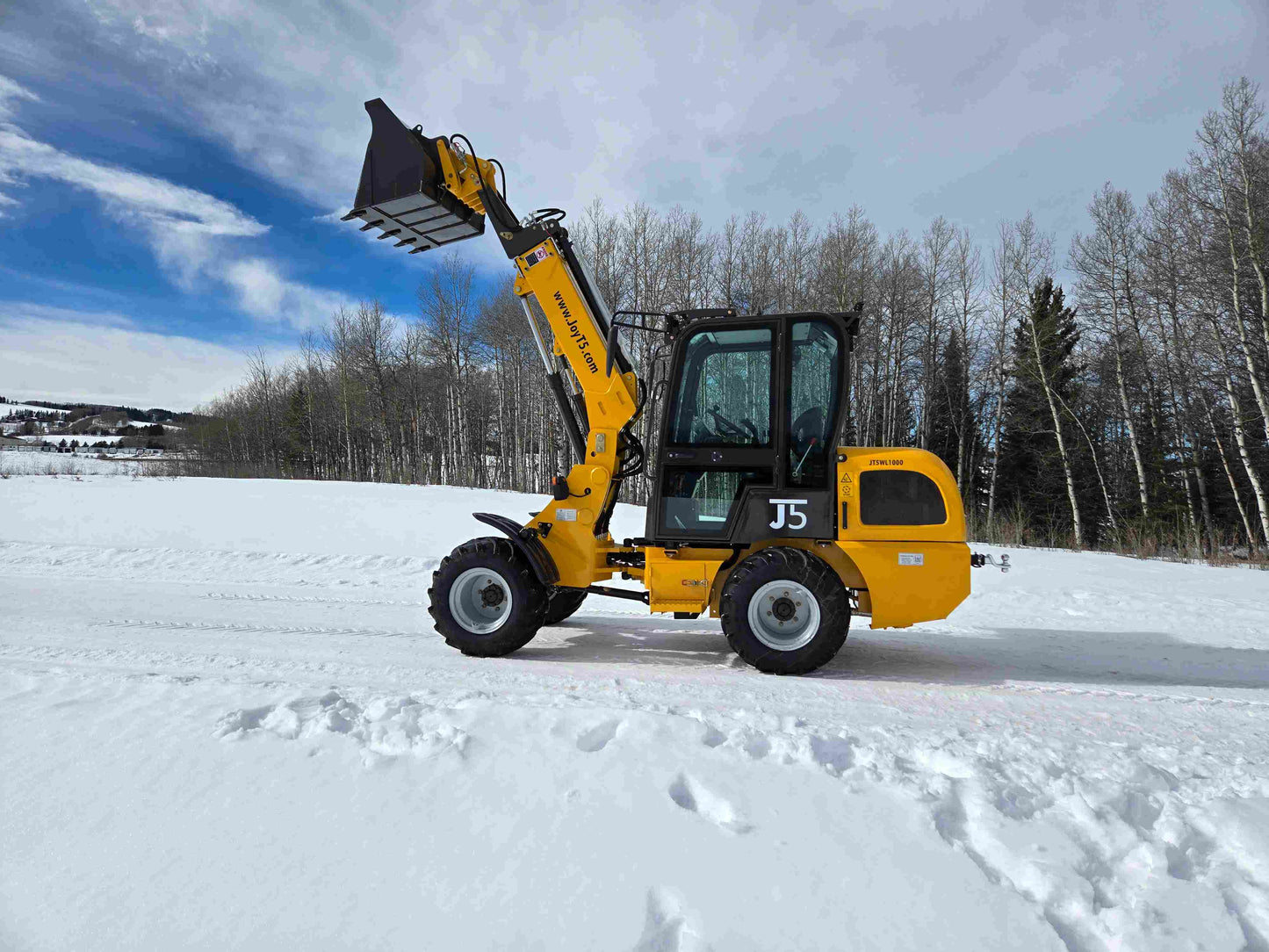 JT5WL1000 compact wheel loader 1 ton operating in snow with raised bucket for landscaping construction and farm use in Canada