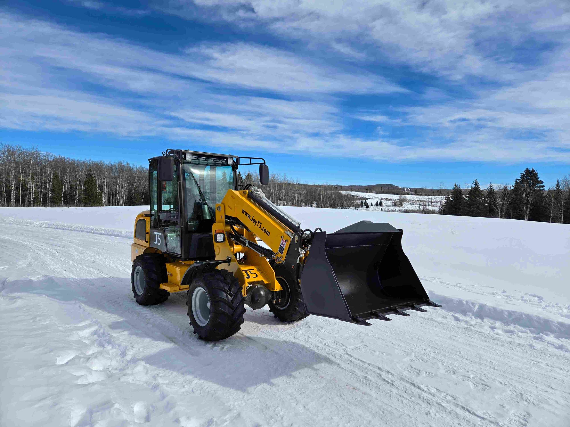 JT5WL1000 compact wheel loader with large bucket attachment working on snow covered landscape in Canada for farm landscaping and construction use