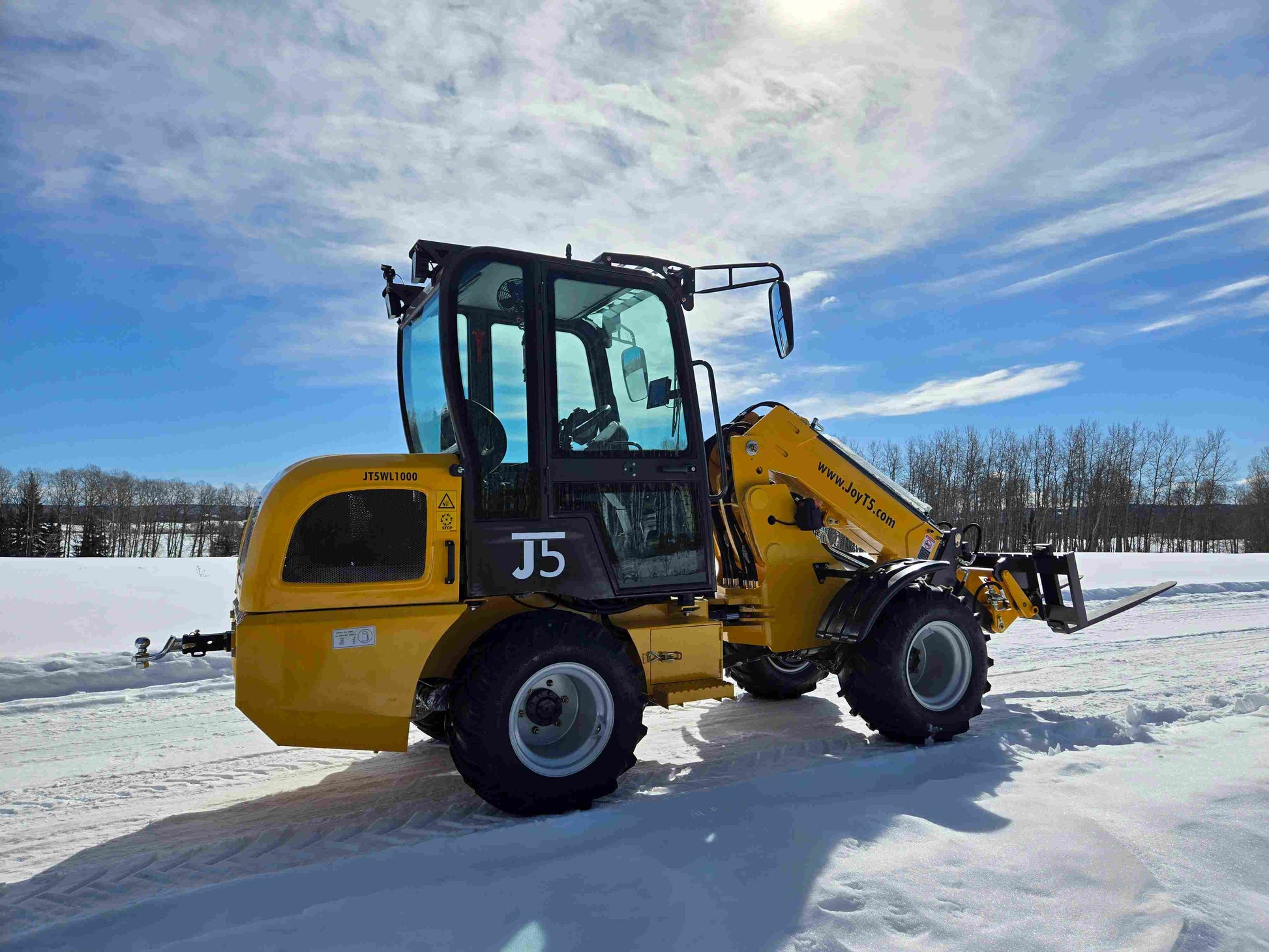 JT5WL1000 compact wheel loader lifting pallet forks in snowy field for farm and construction use in Canada