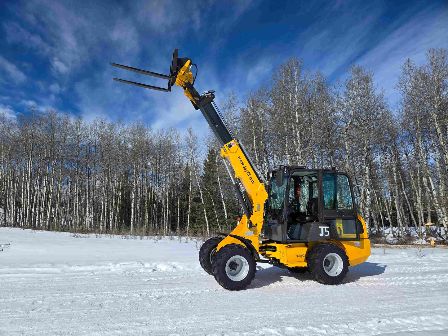 JT5WL1000 compact wheel loader lifting pallet forks in snowy landscape for farm and construction use in Canada