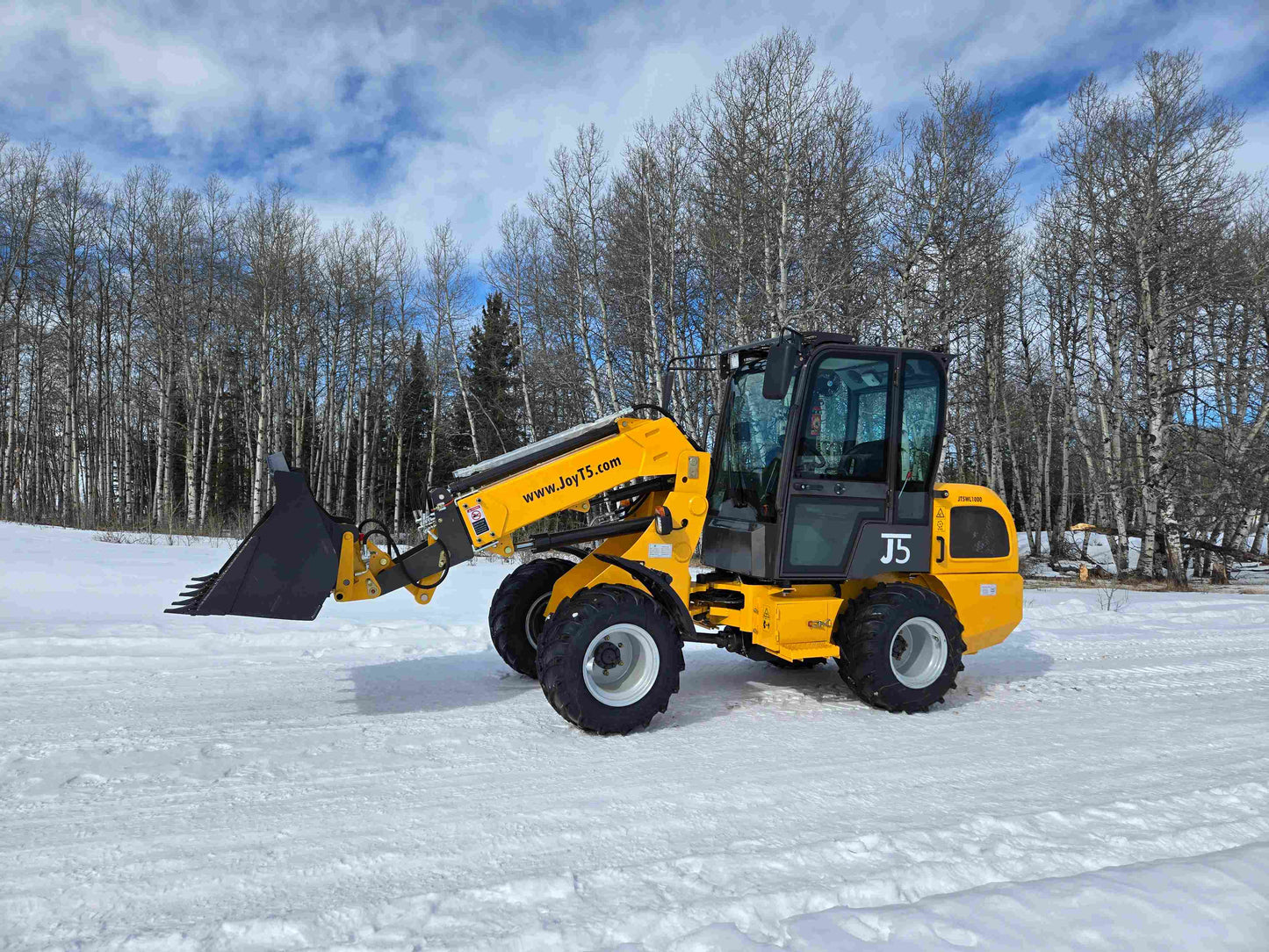 JT5WL1000 compact wheel loader with forklift attachment operating in snow for farm landscaping and construction work in Canada