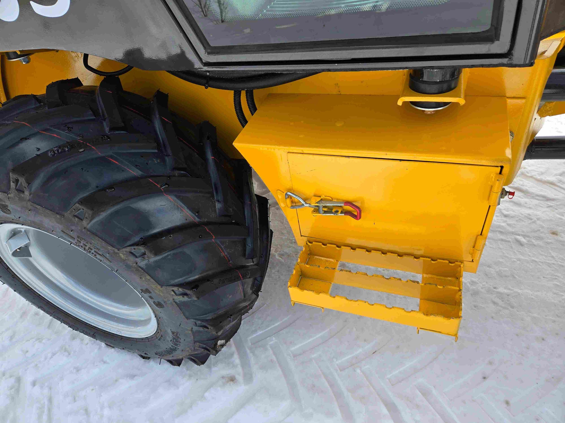 JT5WL1000 compact wheel loader showing safe step access box and rear tire for farm and construction use in snowy Canada