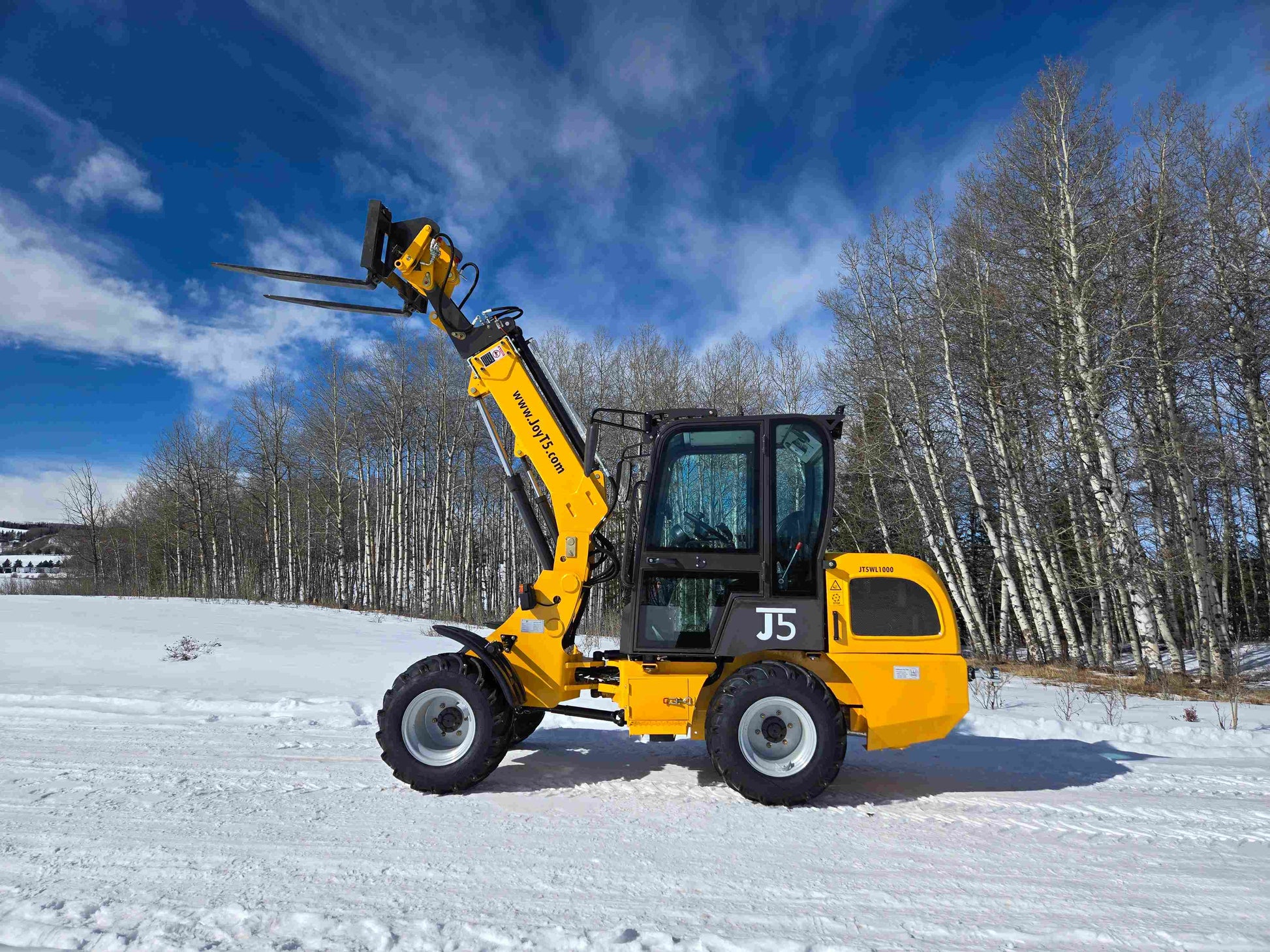 JT5WL1000 compact wheel loader lifting pallet forks on snowy job site in Canada ideal for farm and construction material handling
