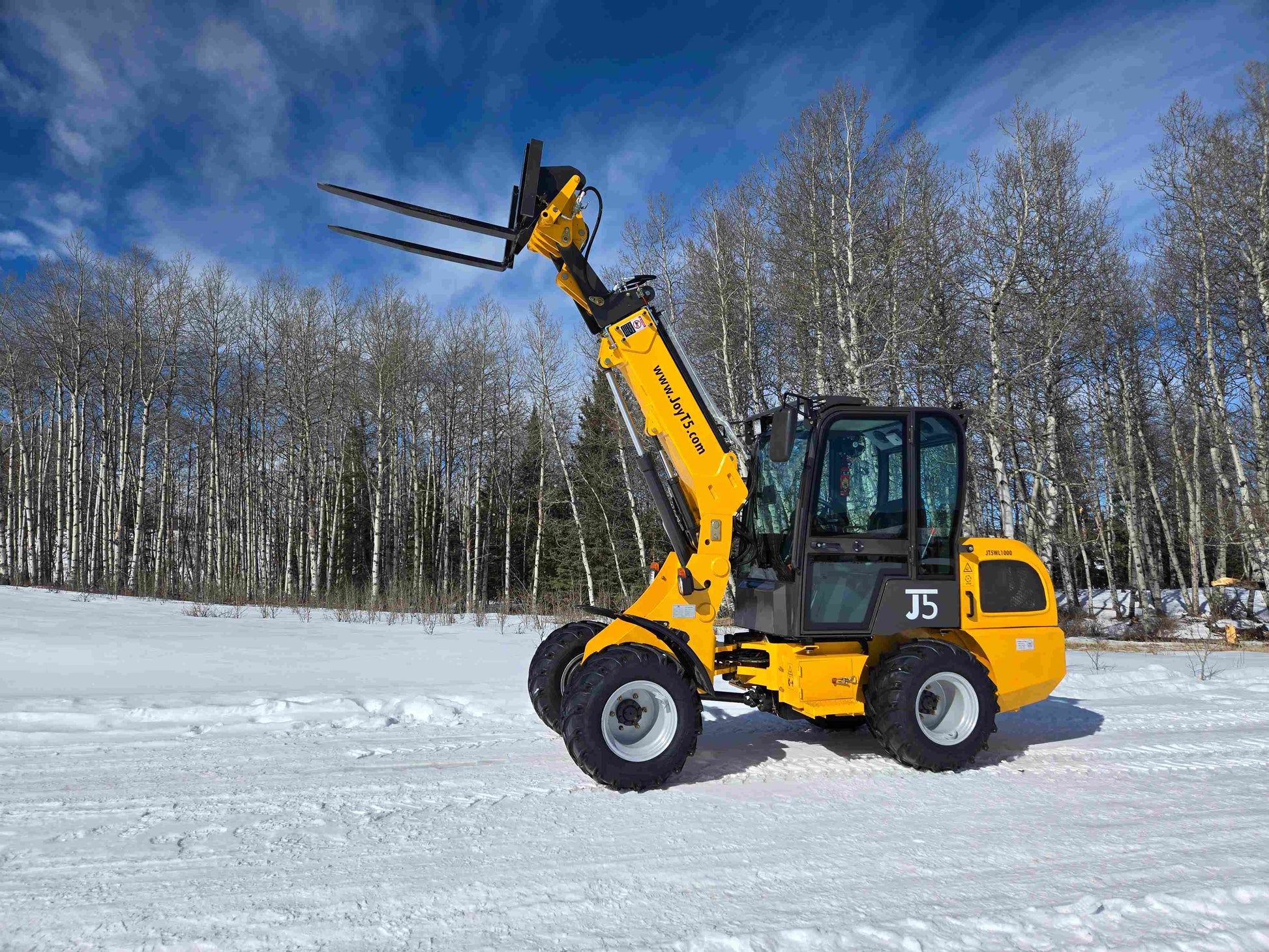JT5WL1000 compact wheel loader lifting pallet forks in snowy field for farm and construction use in Canada