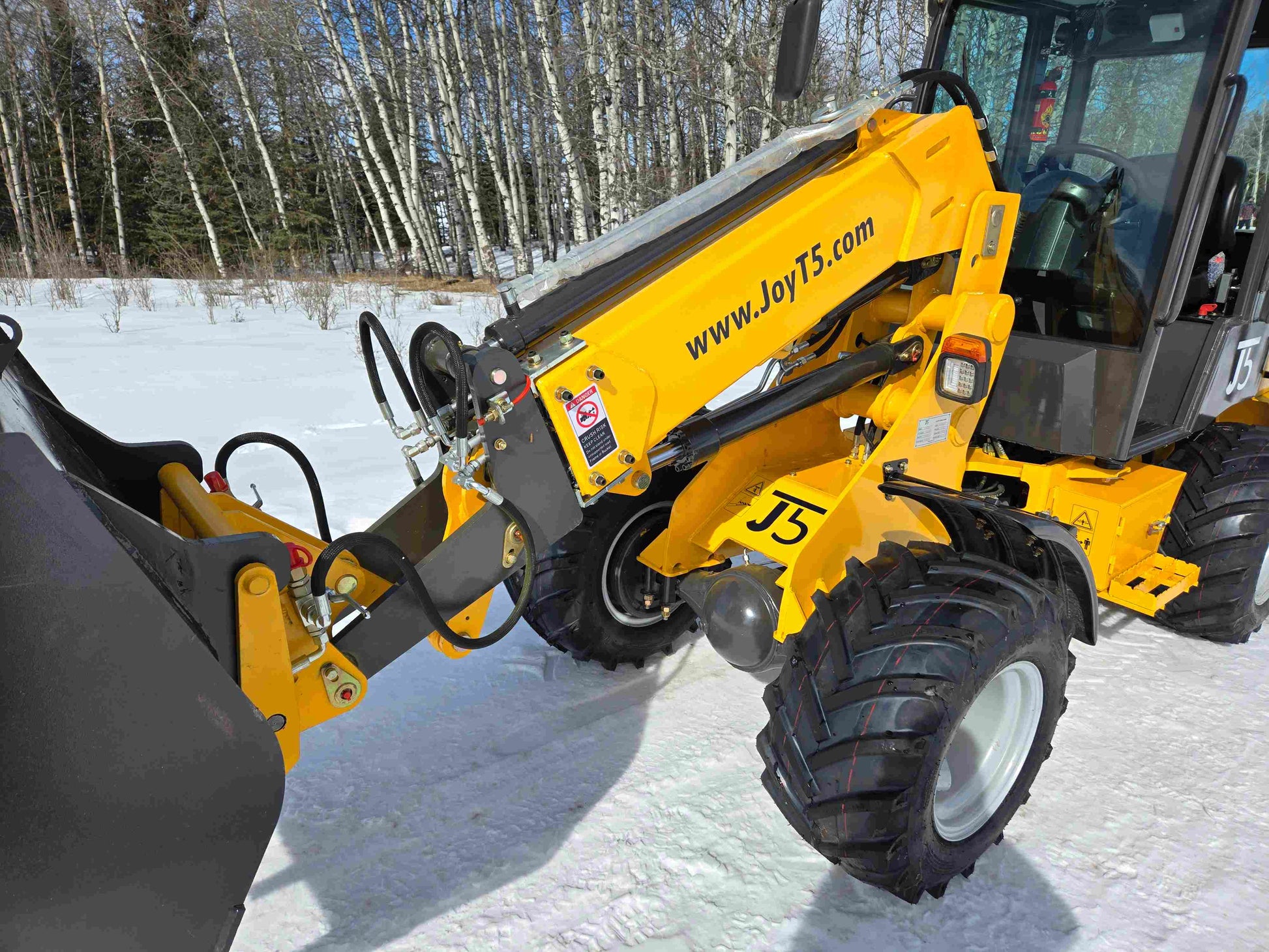 JT5WL1000 compact wheel loader hydraulic arm and bucket linkage closeup working on snow in Canada for farm and construction use