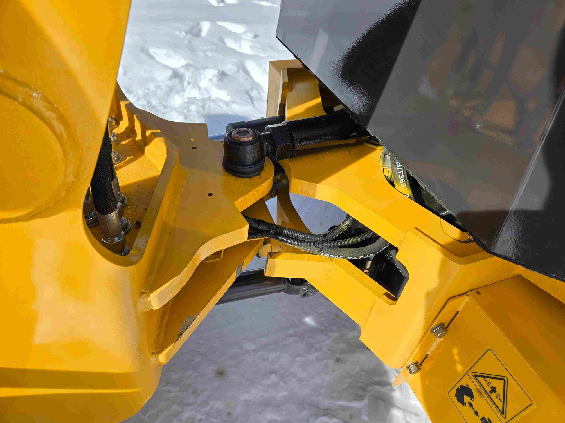 JT5WL1000 compact wheel loader hydraulic steering joint showing heavy duty articulation for farm and construction use in snowy Canada
