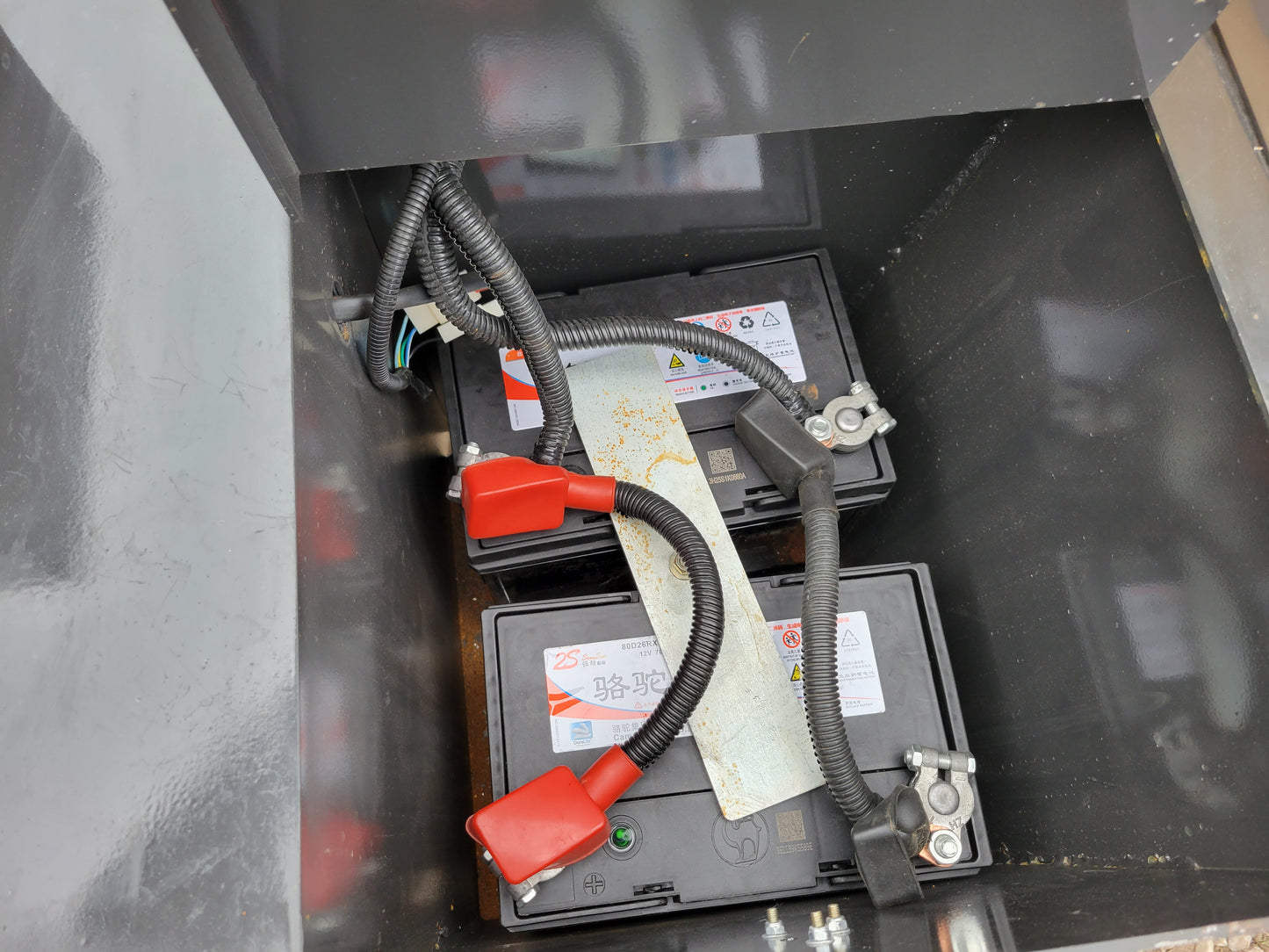 JT5WL1000 wheel loader battery compartment showing dual heavy-duty batteries with wiring connections.
