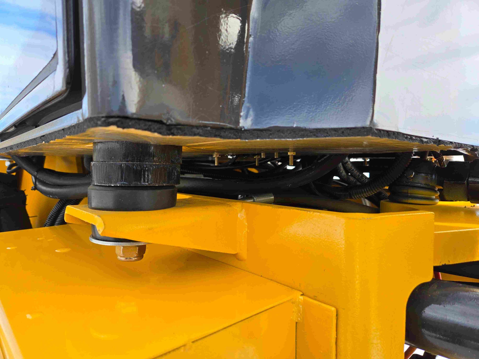 JT5WL1000 wheel loader cabin mounting system with rubber bushings and hydraulic hose connections close-up.