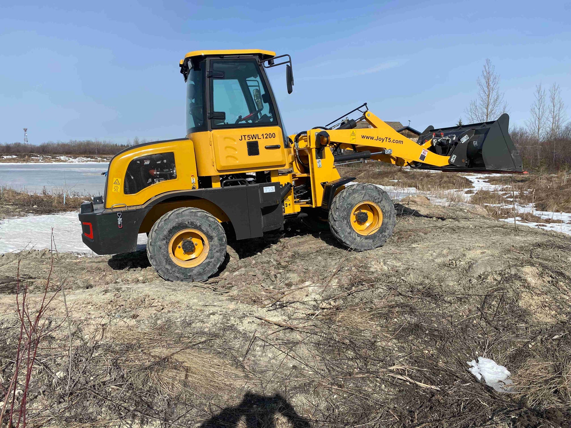 JT5WL1200 compact wheel loader lifting soil for construction and landscaping projects on rough terrain in Canada