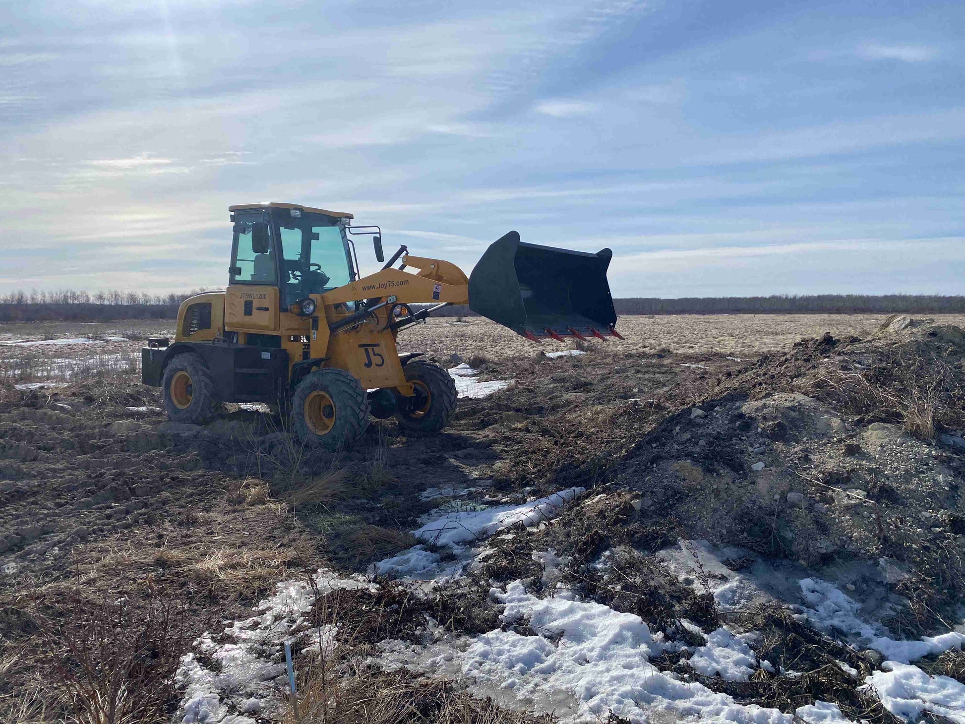 JT5WL1200 compact wheel loader lifting soil with front bucket during construction work and landscaping in Canada