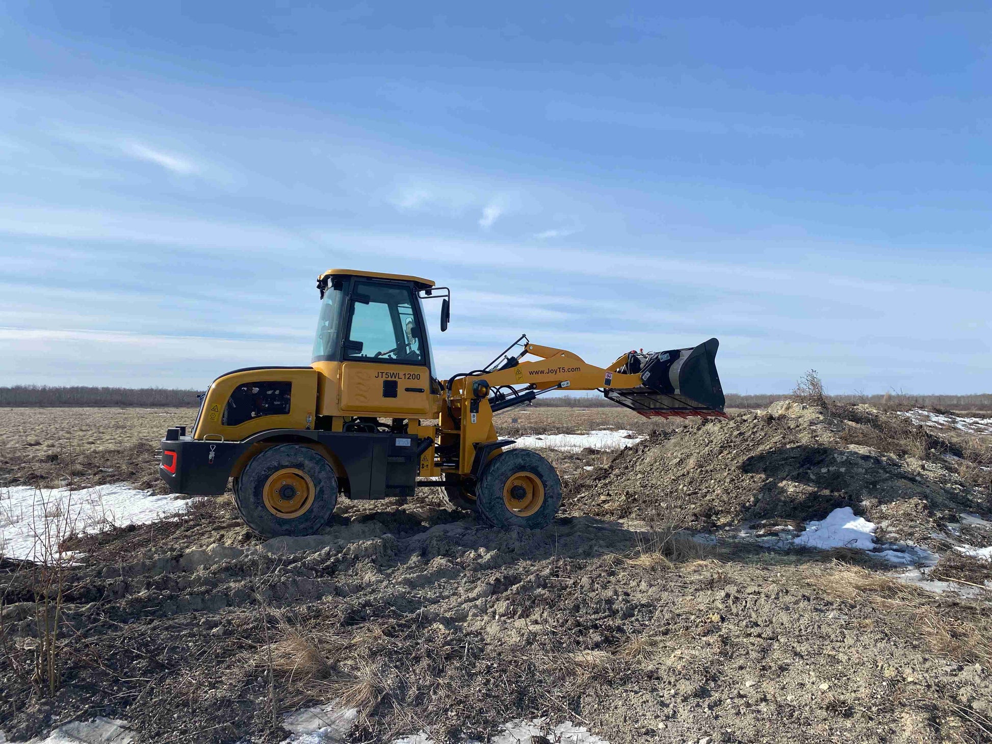 JT5WL1200 compact wheel loader working on farm field lifting soil for landscaping and construction projects in Canada
